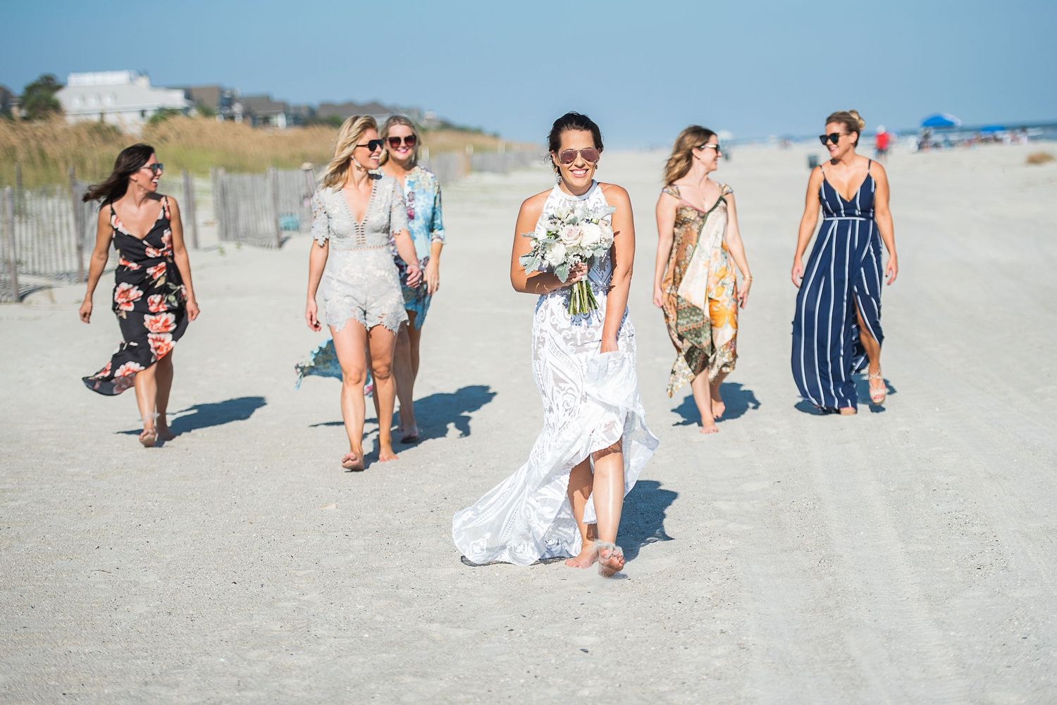 A group enjoying a sunny day together at a sandy beach with blue skies in the background.