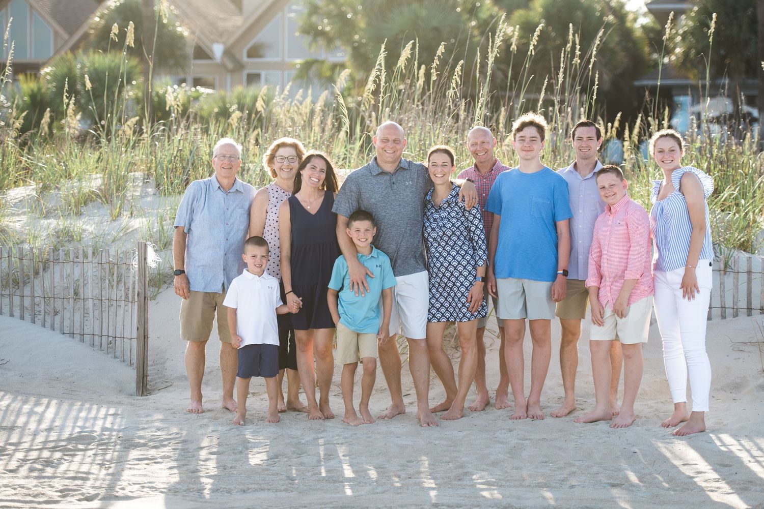 Casual beach photo of multiple generations standing together on sandy pathway with fencing.Hammock Beach, Sea Pines coastal photography.