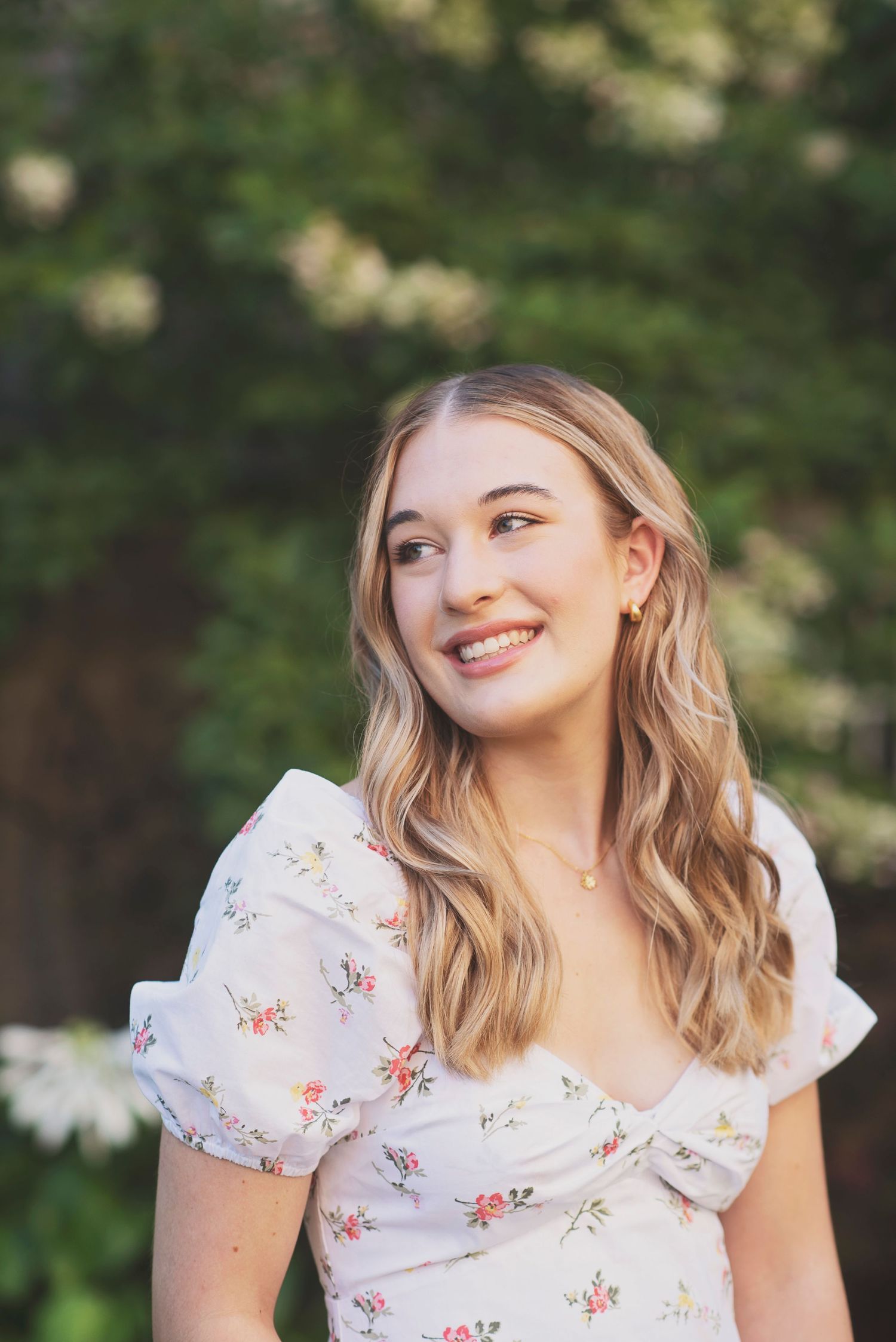 Outdoor portrait in floral dress with natural sunlit background.