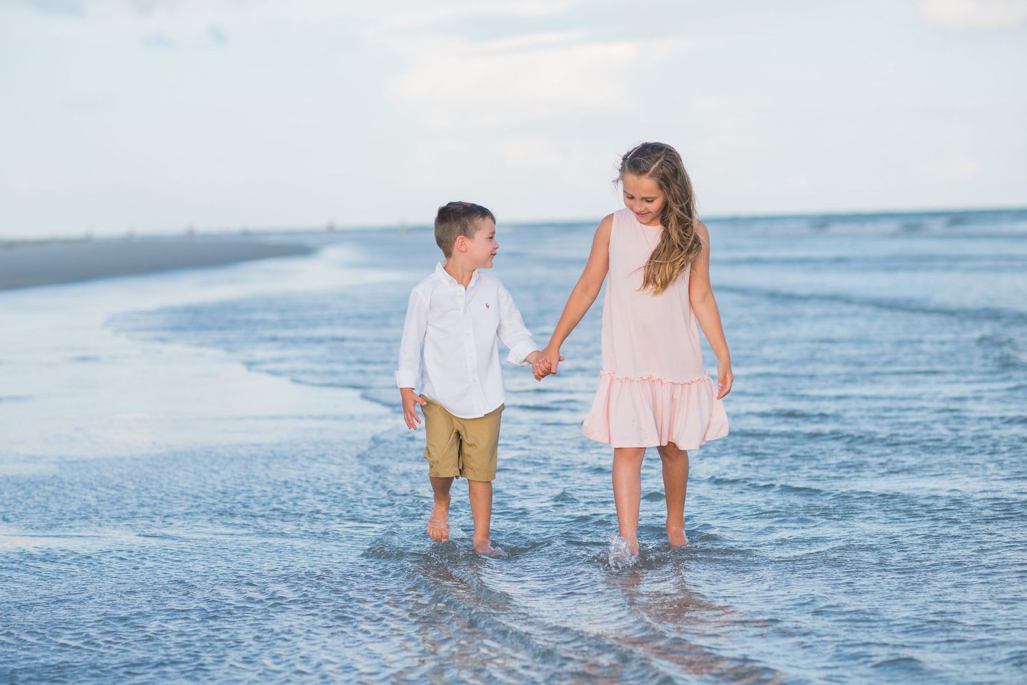 Children playing at water's edge during sunset beach photo session.