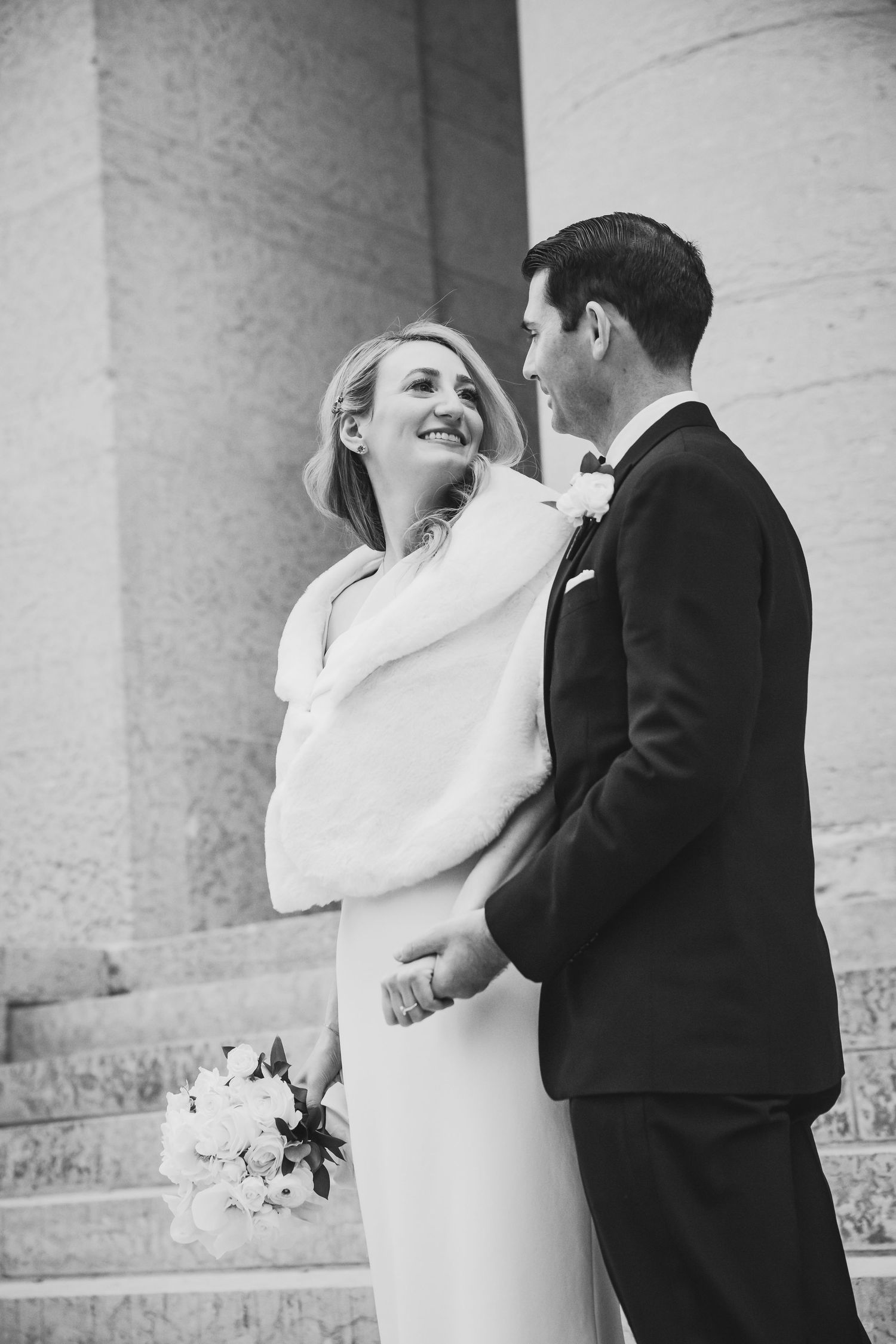 Black and white intimate wedding portrait against white columned architecture.