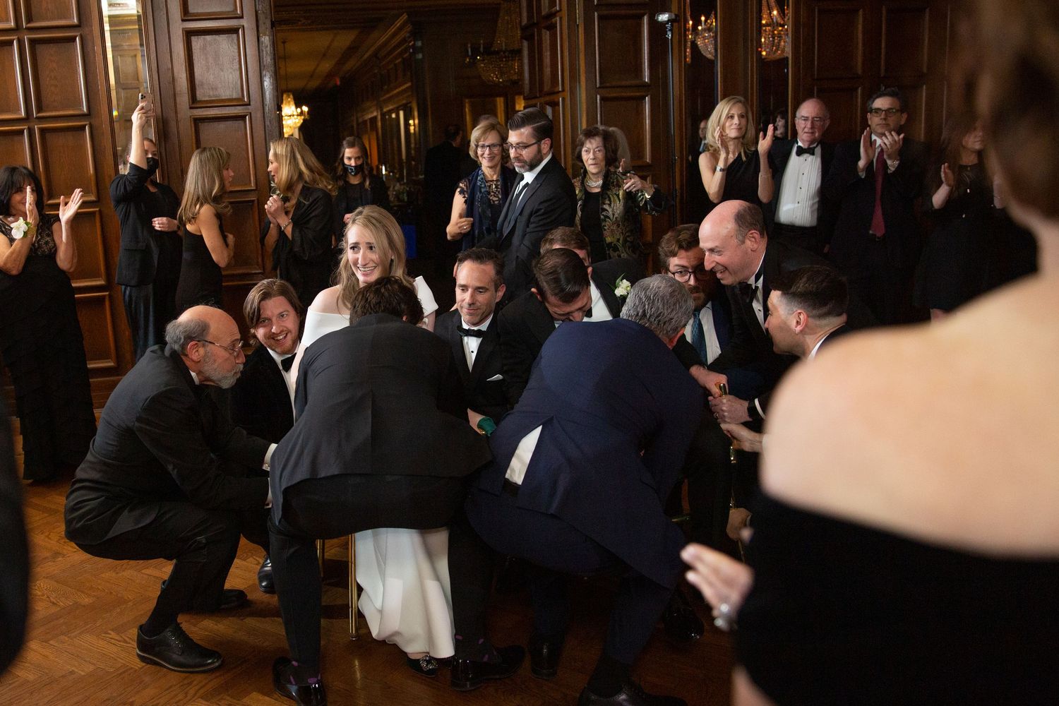 Wedding guests gathered in celebration at wood-paneled reception venue.