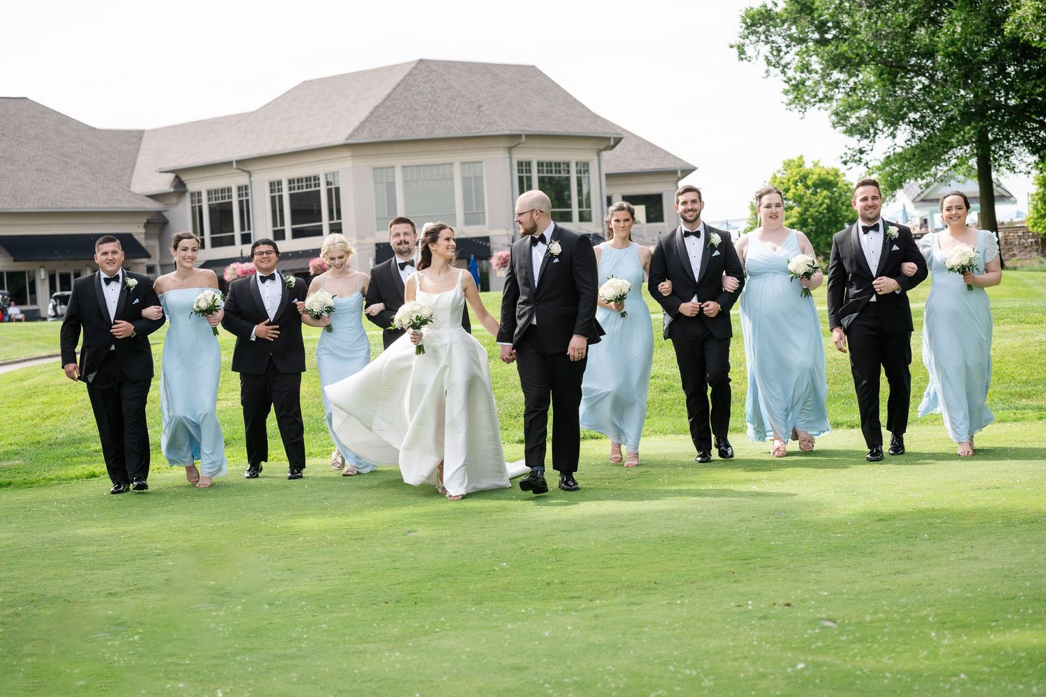 Palm Coast Conservatory Wedding party in formal attire poses on a lush green lawn during an outdoor celebration.