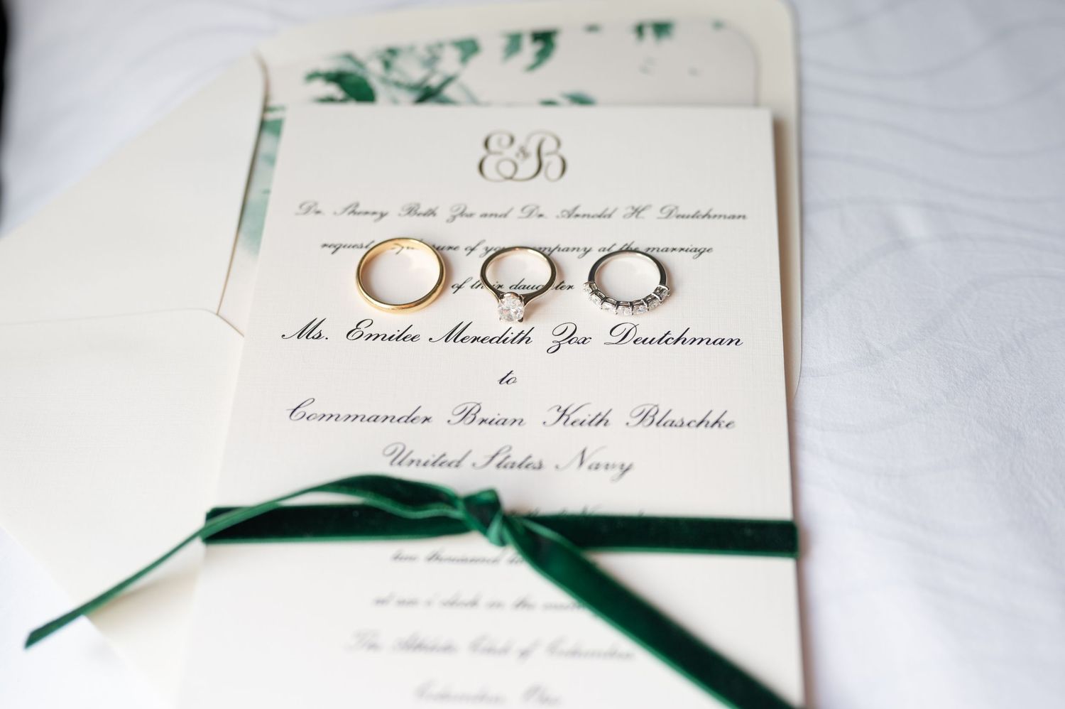 Elegant wedding invitation with green ribbon and monogram details.
