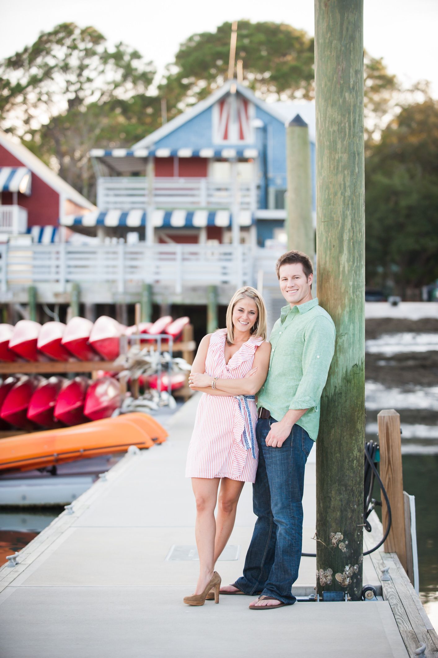 A Hilton Head couple poses together at South Beach Marina, Hilton Head with red and white striped boat rentals in the background.