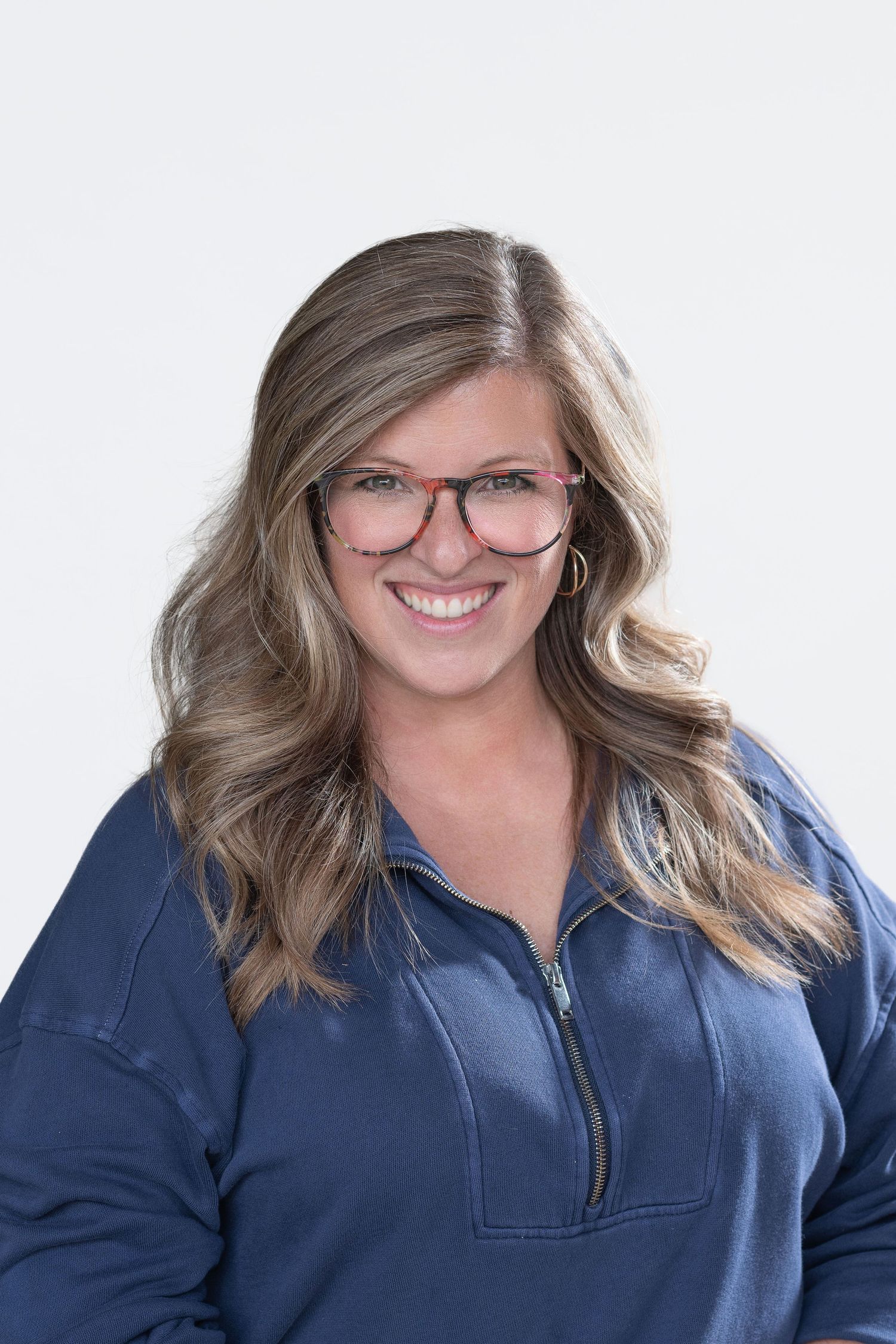 Professional headshots of a person wearing glasses and a blue denim shirt against white background.