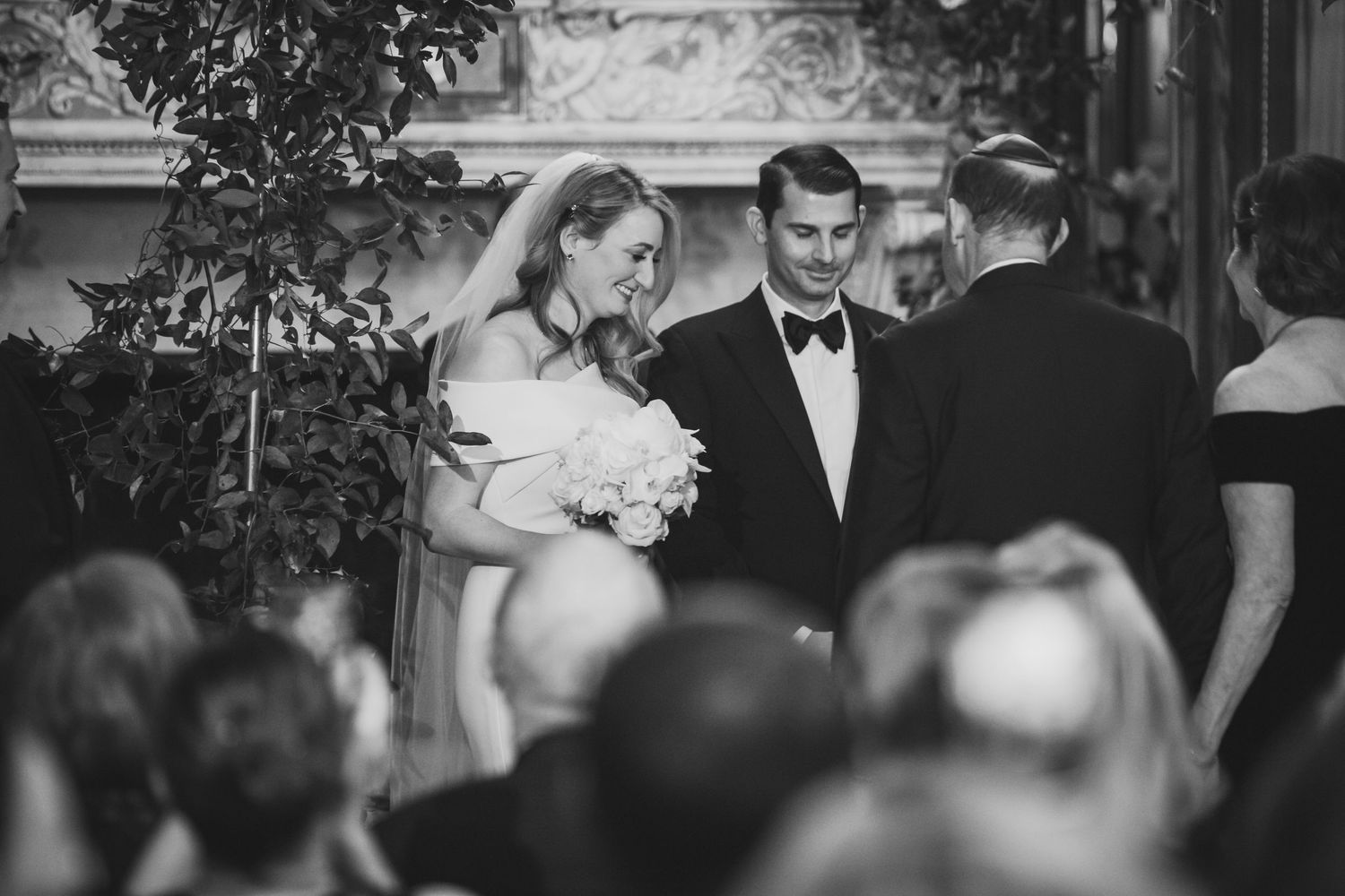 Wedding ceremony guests gather outdoors under trees for an intimate celebration.