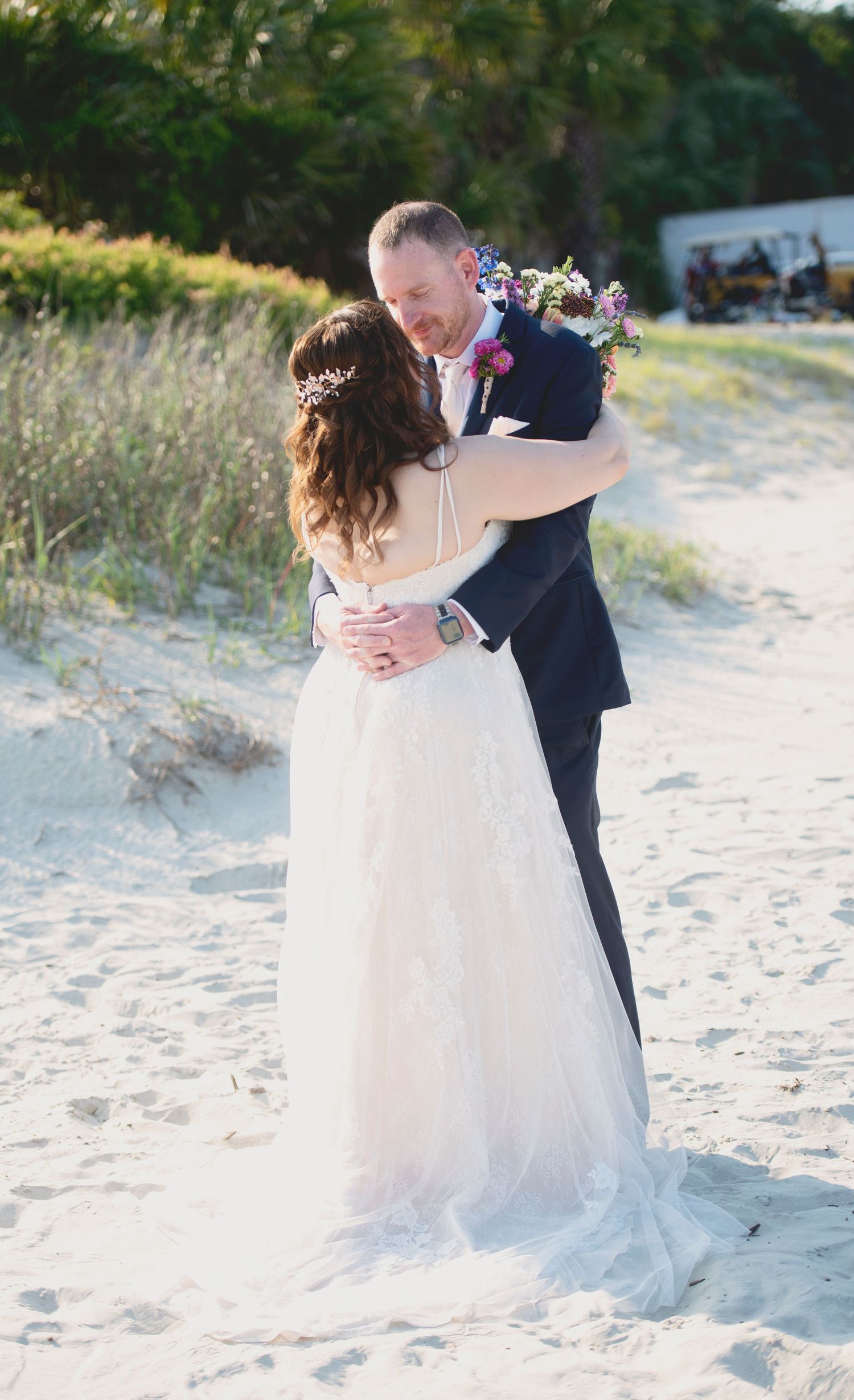Newlyweds share an intimate moment while dancing on a sandy beach.