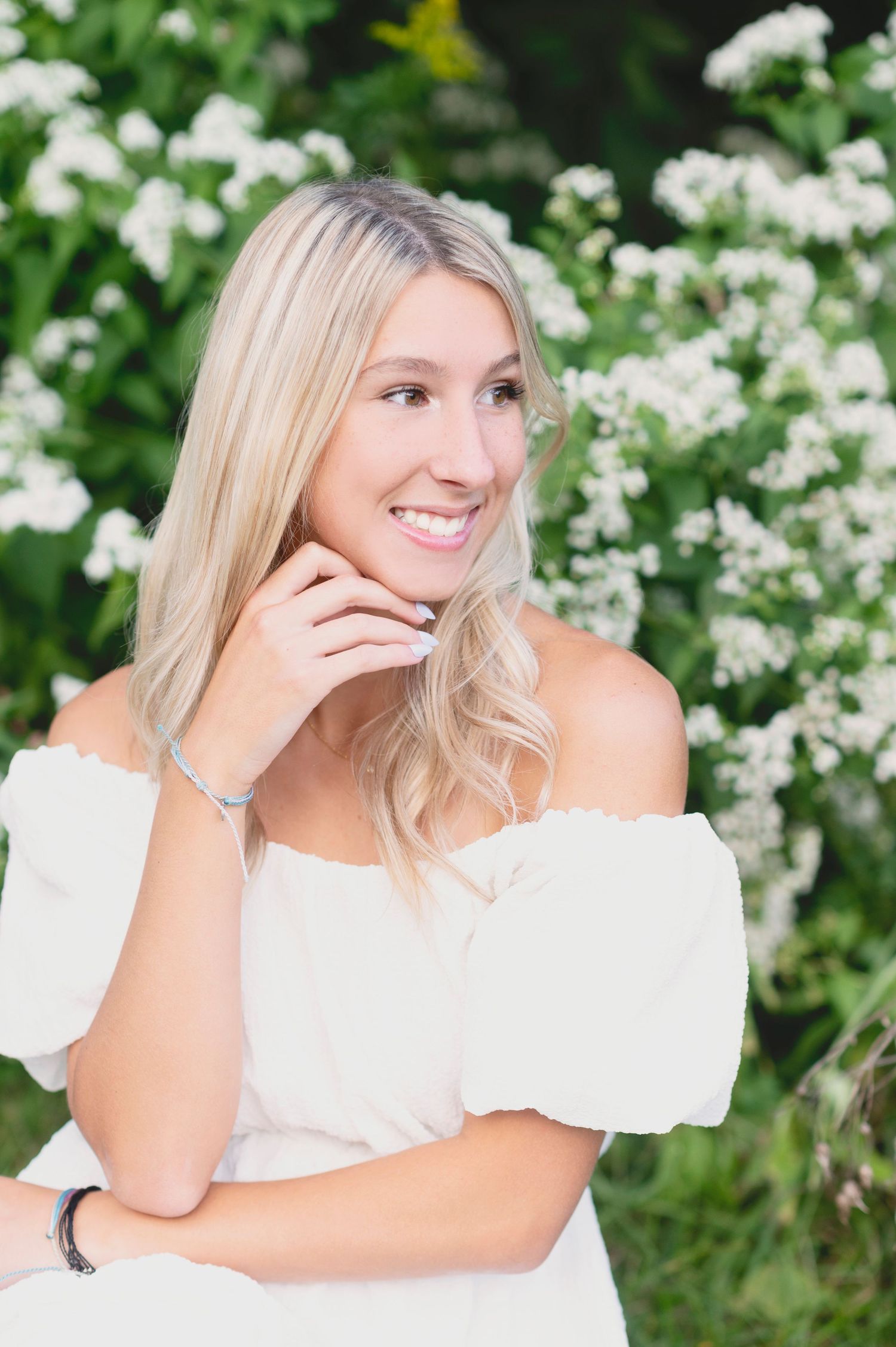 A joyful portrait against white flowering bushes in a garden setting.