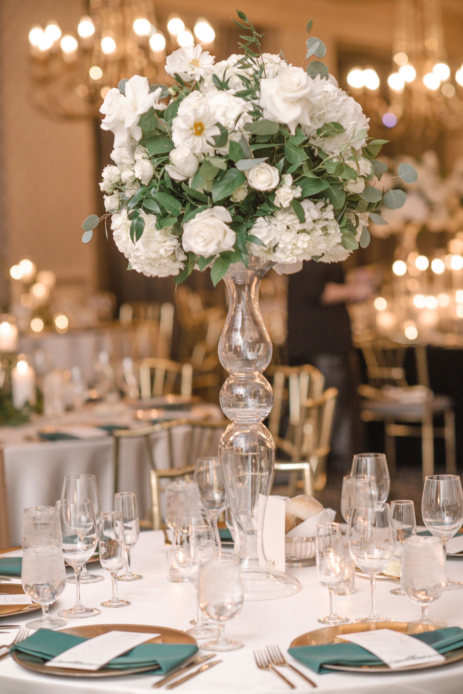 Elegant wedding reception tables set with white floral centerpieces and teal accents.