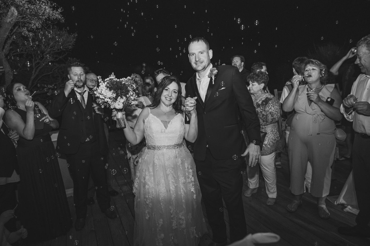 Black and white photo of wedding guests dancing and celebrating at a reception.