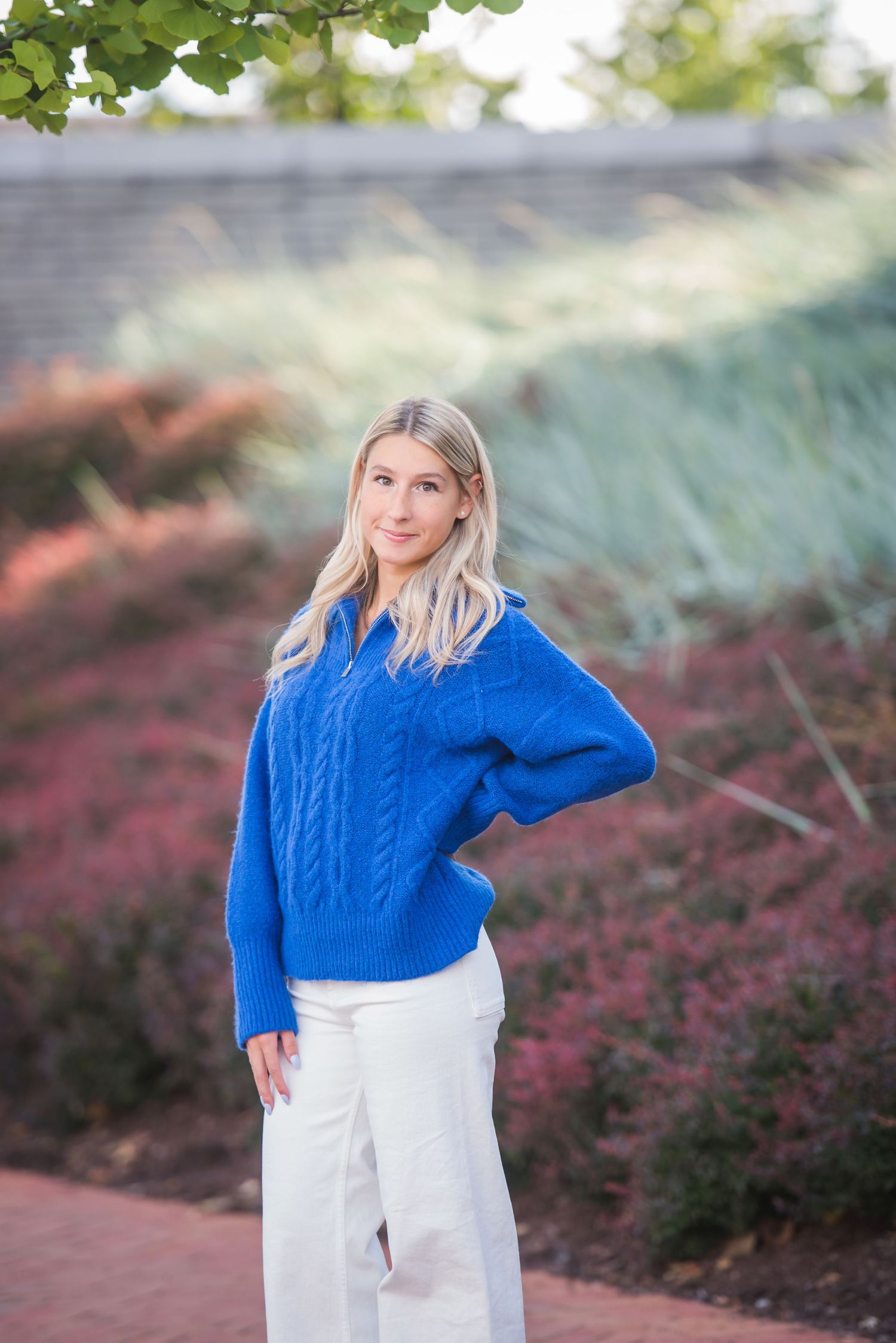 A bright blue cable knit sweater paired with white pants creates a casual outdoor look.