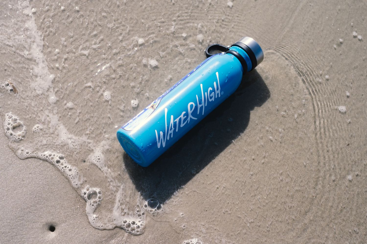 Blue water bottles lying on wet sand at the beach.