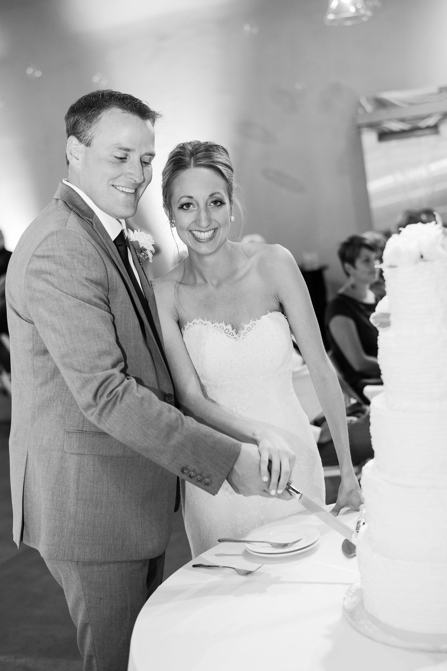 A black and white wedding photo sequence showing a couple cutting their wedding cake together at the reception.