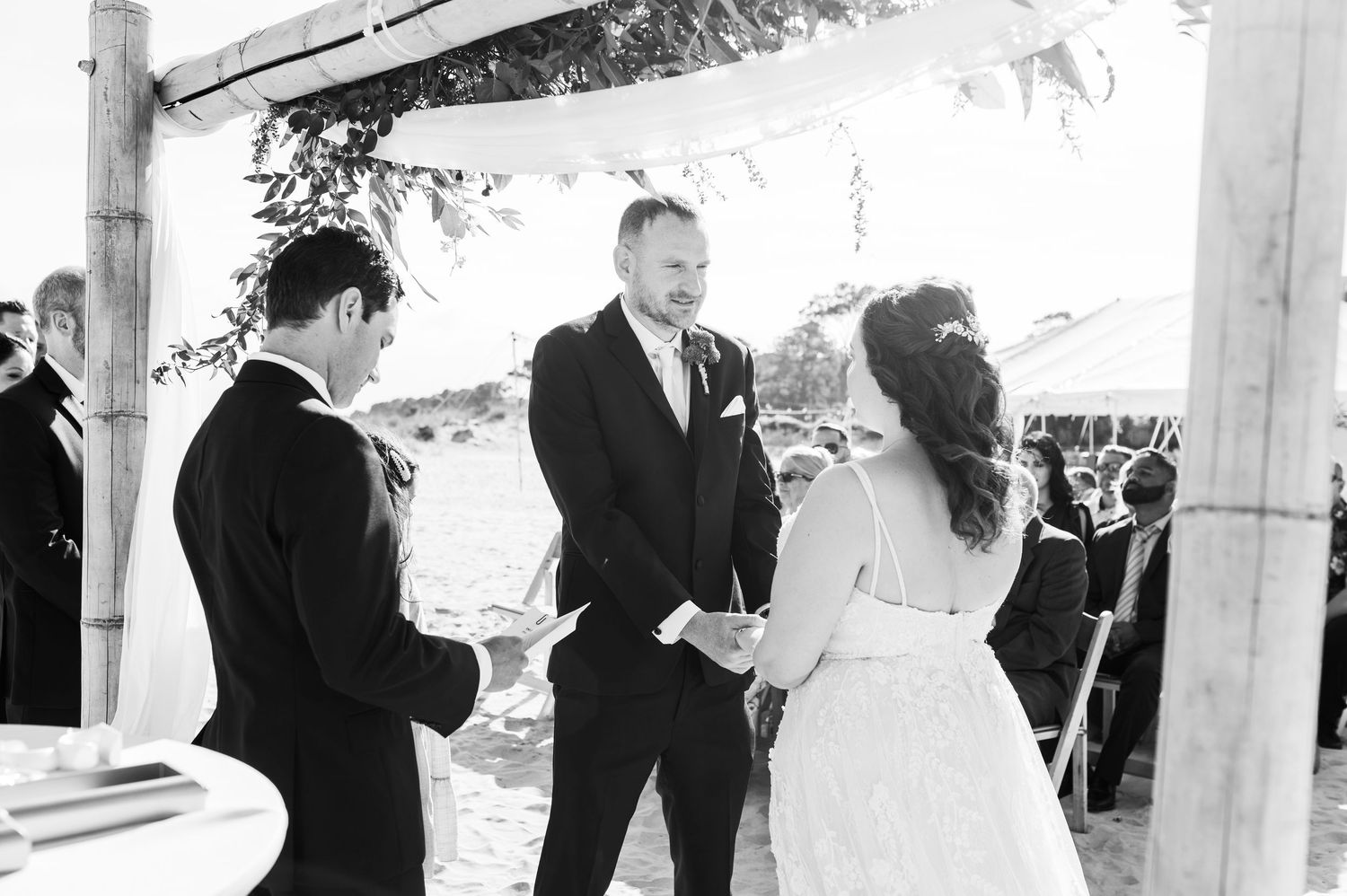 Wedding ceremony moments captured in black and white under outdoor tent.