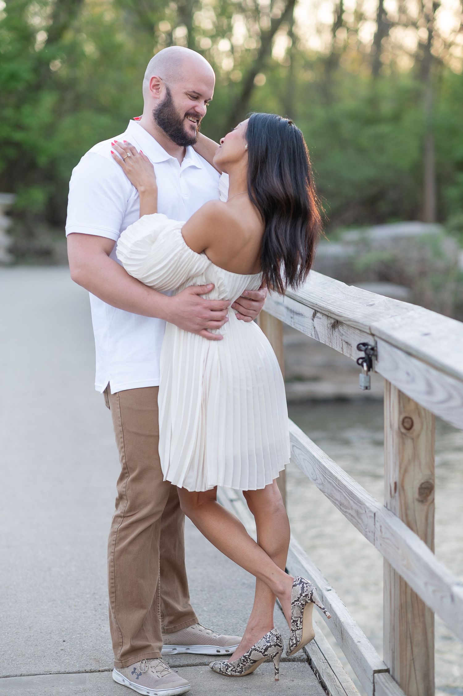 Romantic couple poses along wooden railing during outdoor photo session. Washington Oaks Garden, Palm Coast engagement