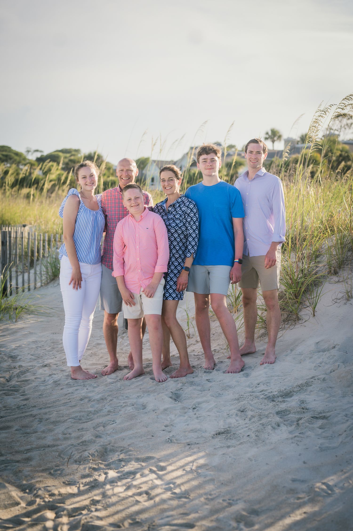 Extended family group photo on beach sand dune at sunset.