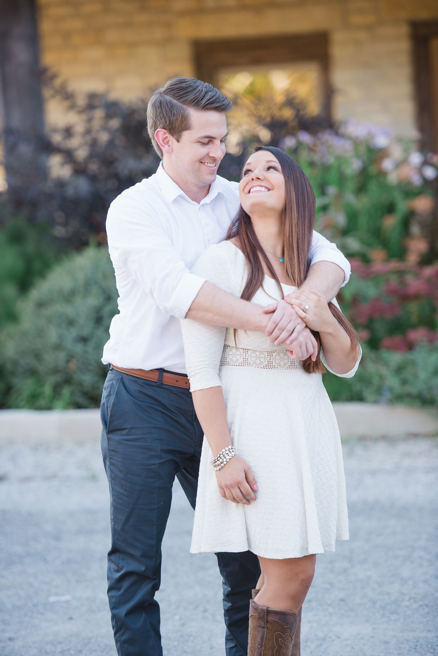 Playful couple shares intimate moment outdoors against stone wall backdrop.