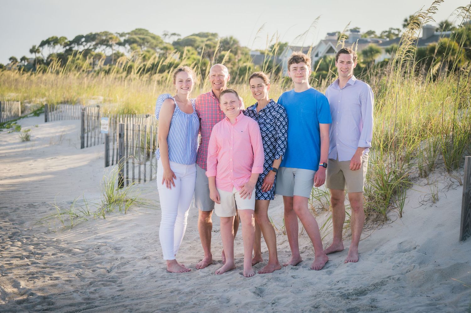 Family group photos on beach boardwalk with sea oats and dunes at golden hour.