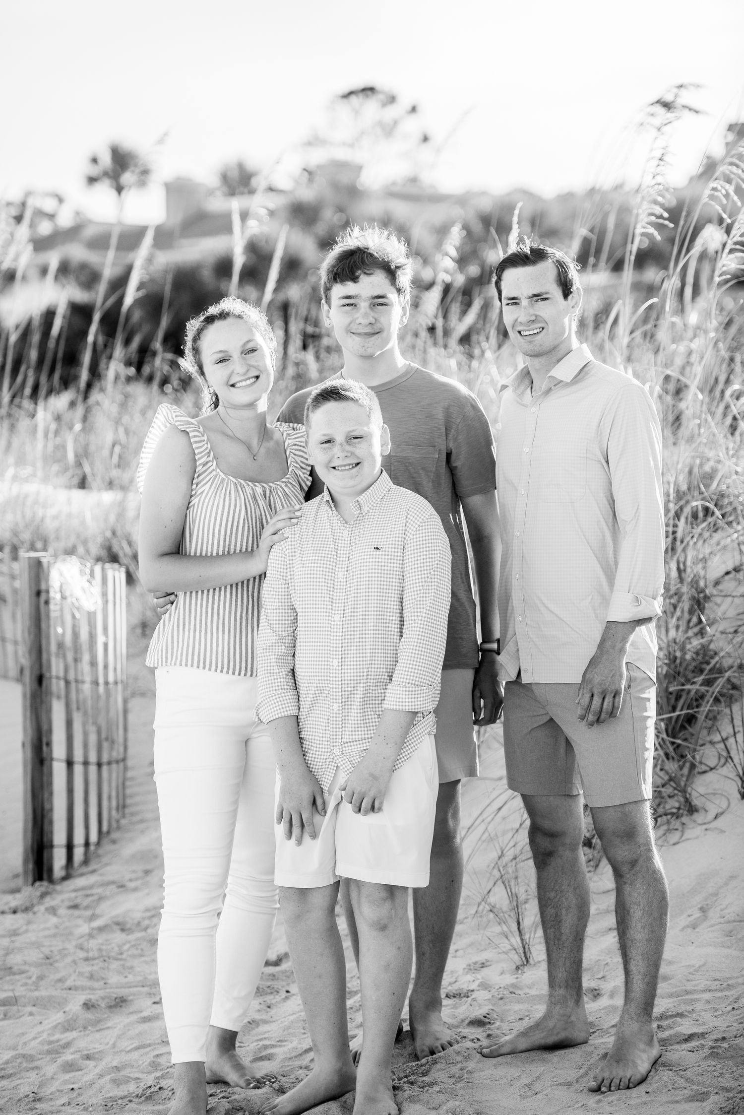 Black and white portrait of a family group smiling together on a sandy beach with sea grass and fencing.Hammock Beach, Sea Pines coastal pho
