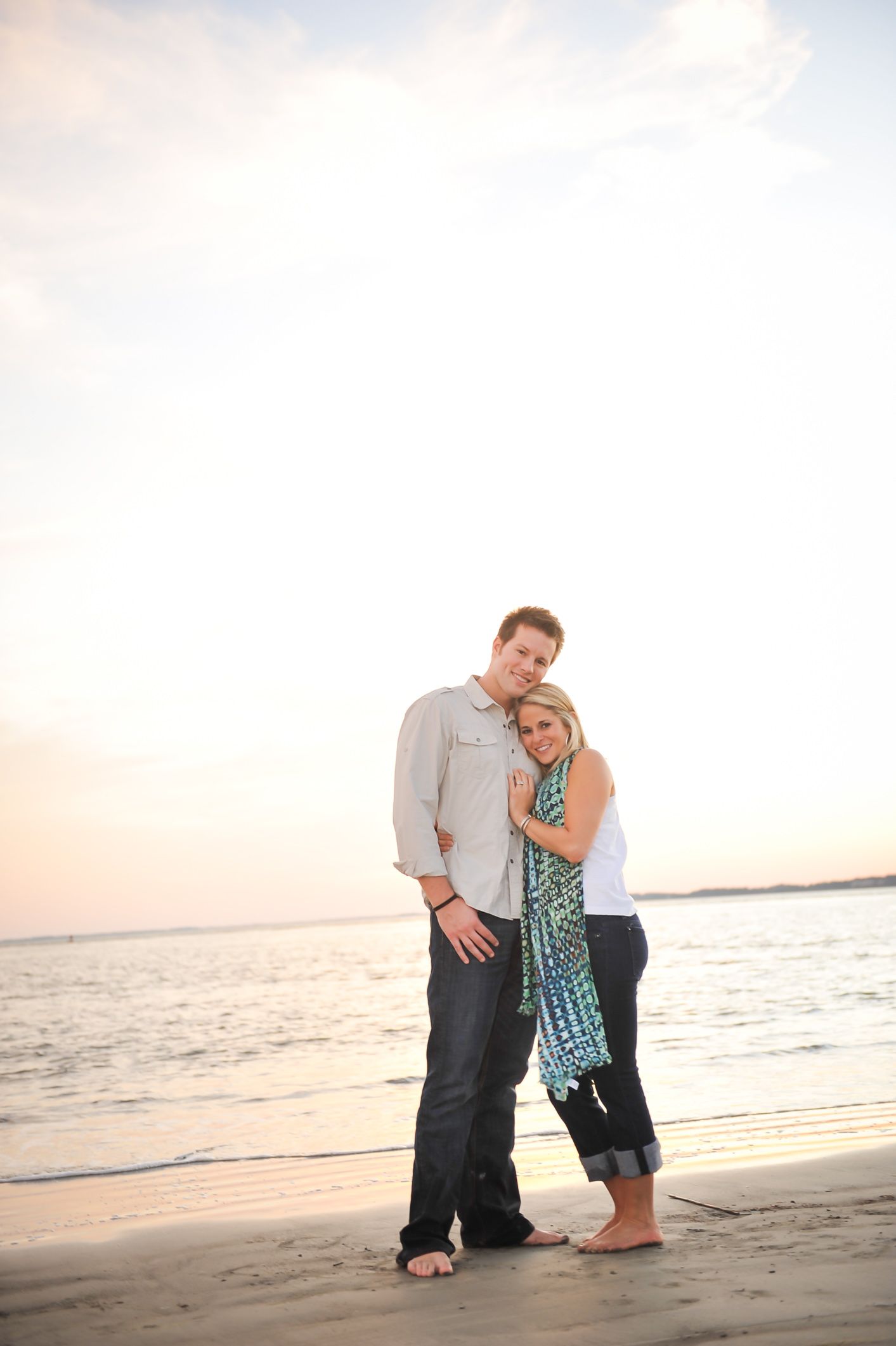A romantic palm coast couple poses together on a beach at sunset, creating a series of tender moments by the ocean.