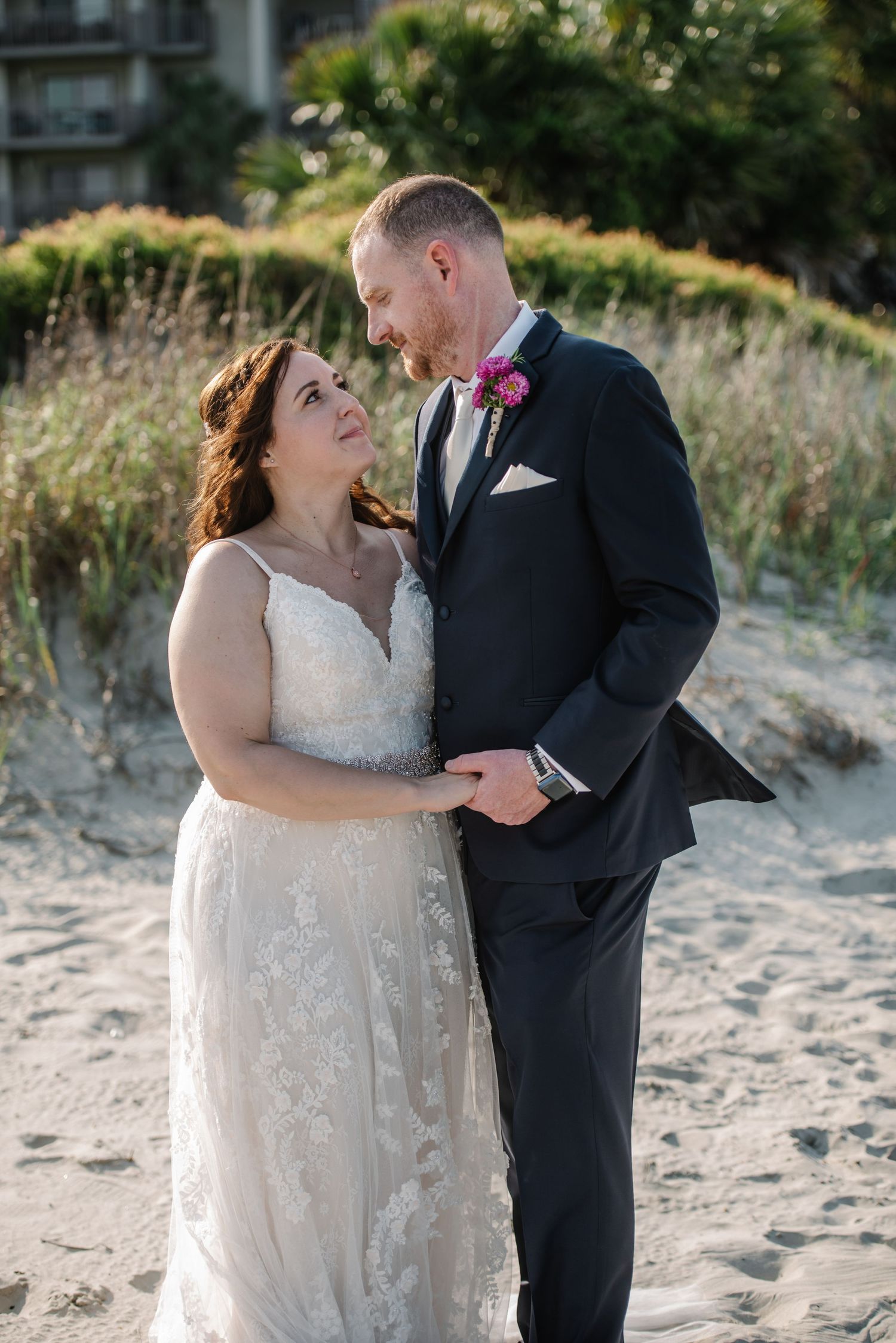 Romantic beach wedding portraits with couple embracing against coastal dunes.