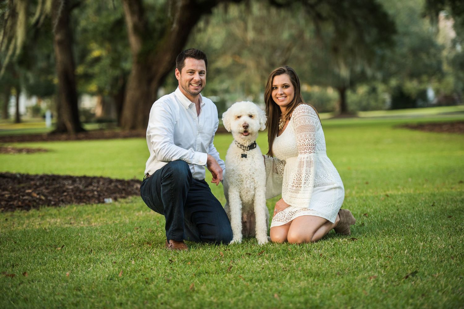 Casual outdoor couple photoshoot with pet dog in park setting.