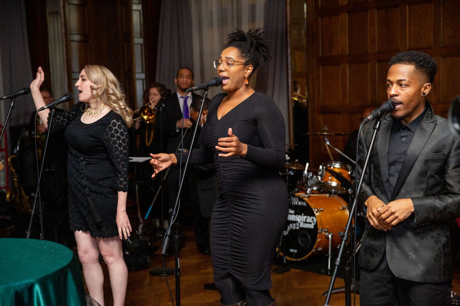 Wedding band performers singing on stage in formal black attire.