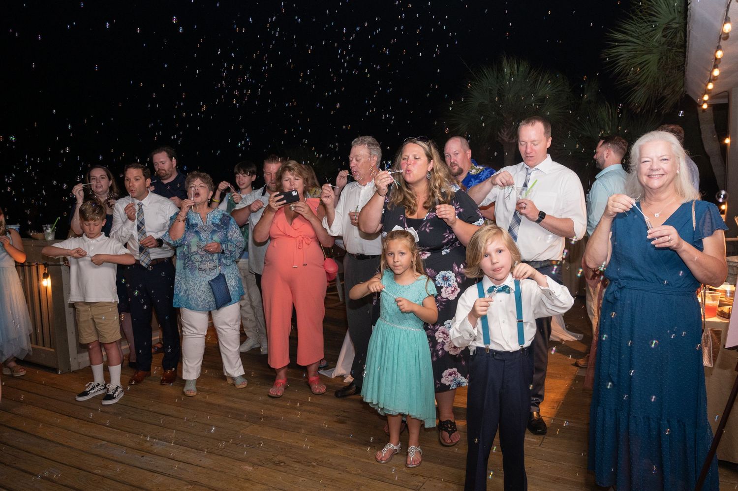 Wedding guests dance and celebrate on a dimly lit dance floor during an evening reception.