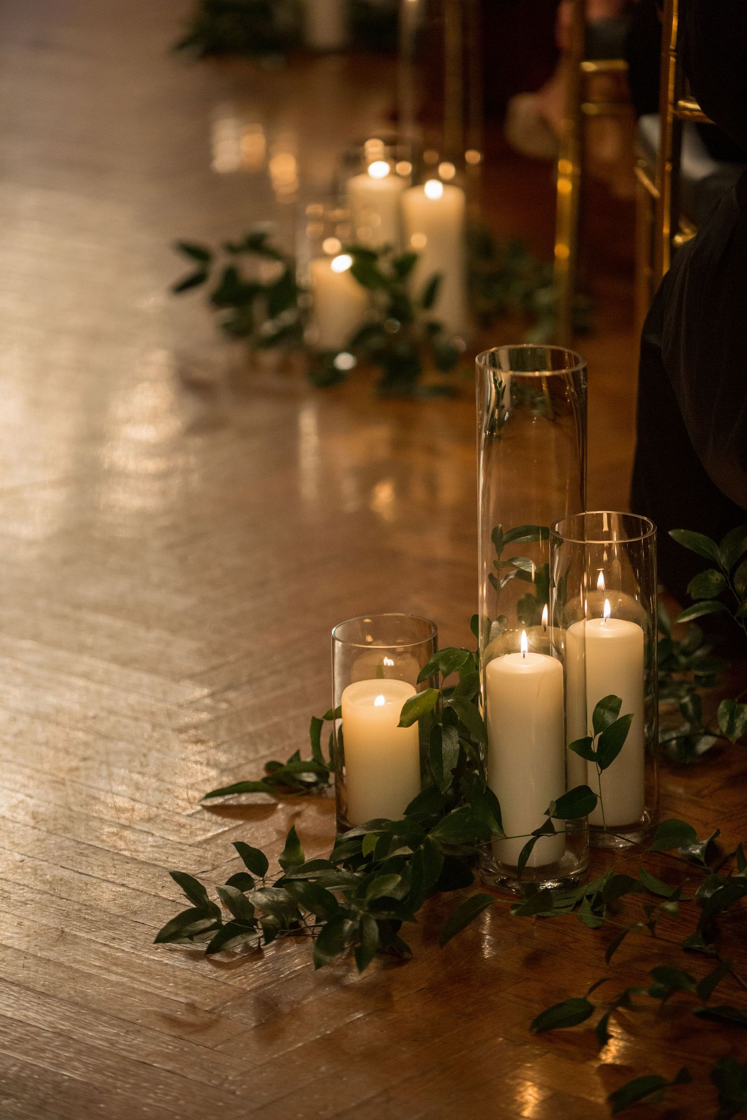 White pillar candles with greenery create an intimate wedding reception atmosphere.