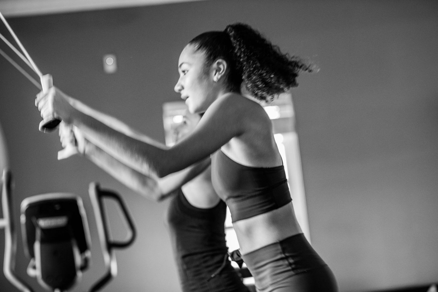 Athletic person performing exercise movements in a black and white gym photo.