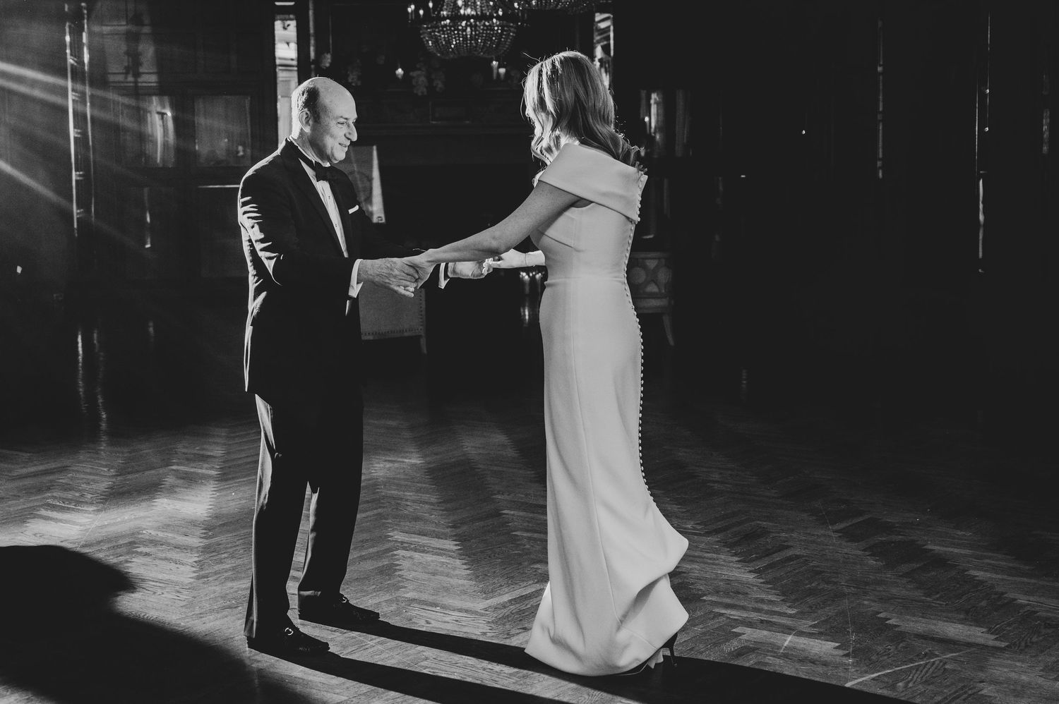 Black and white photo of couple dancing in dramatic lighting.