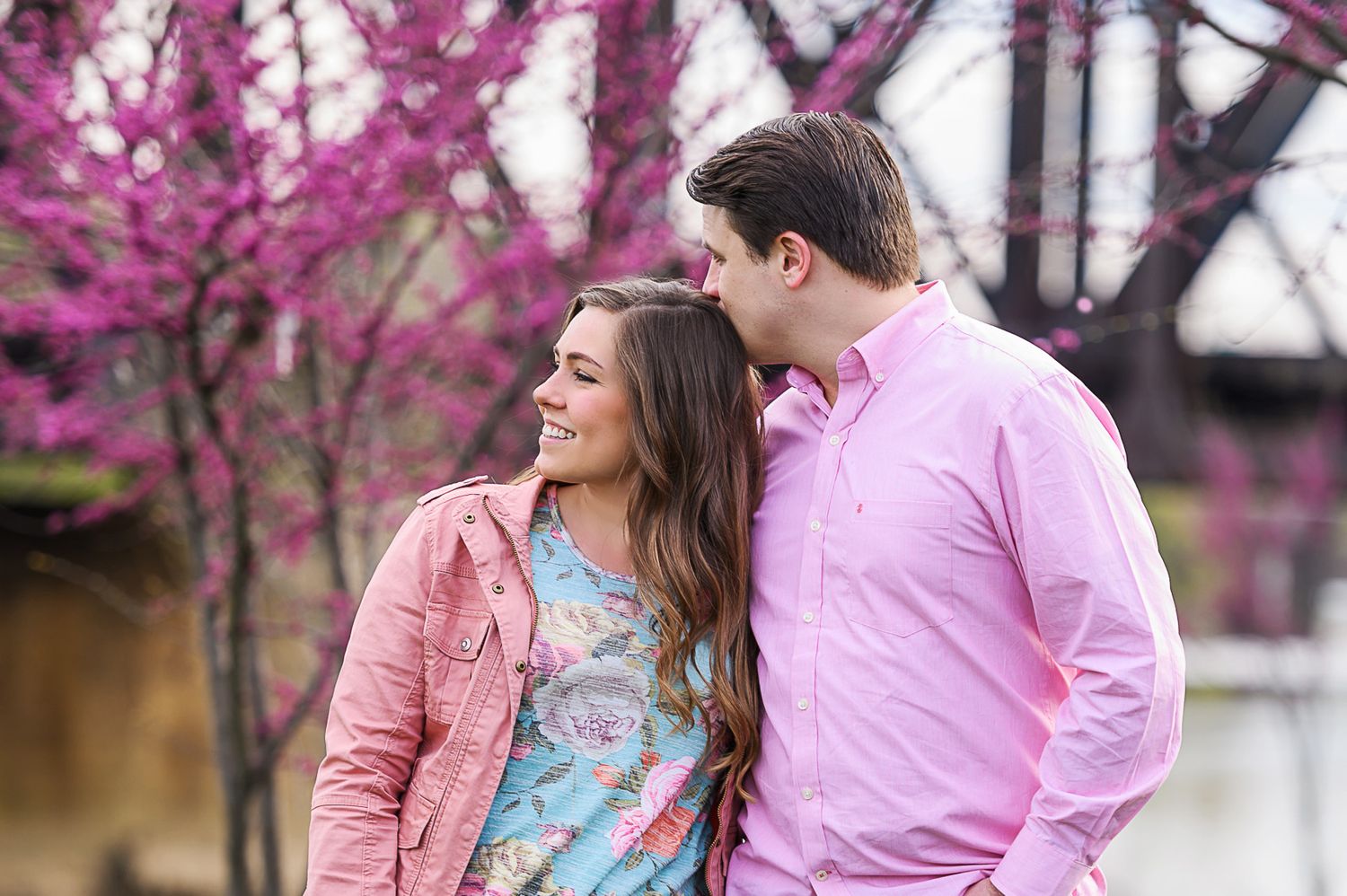 Spring engagement photos with blooming pink cherry blossoms in the background.