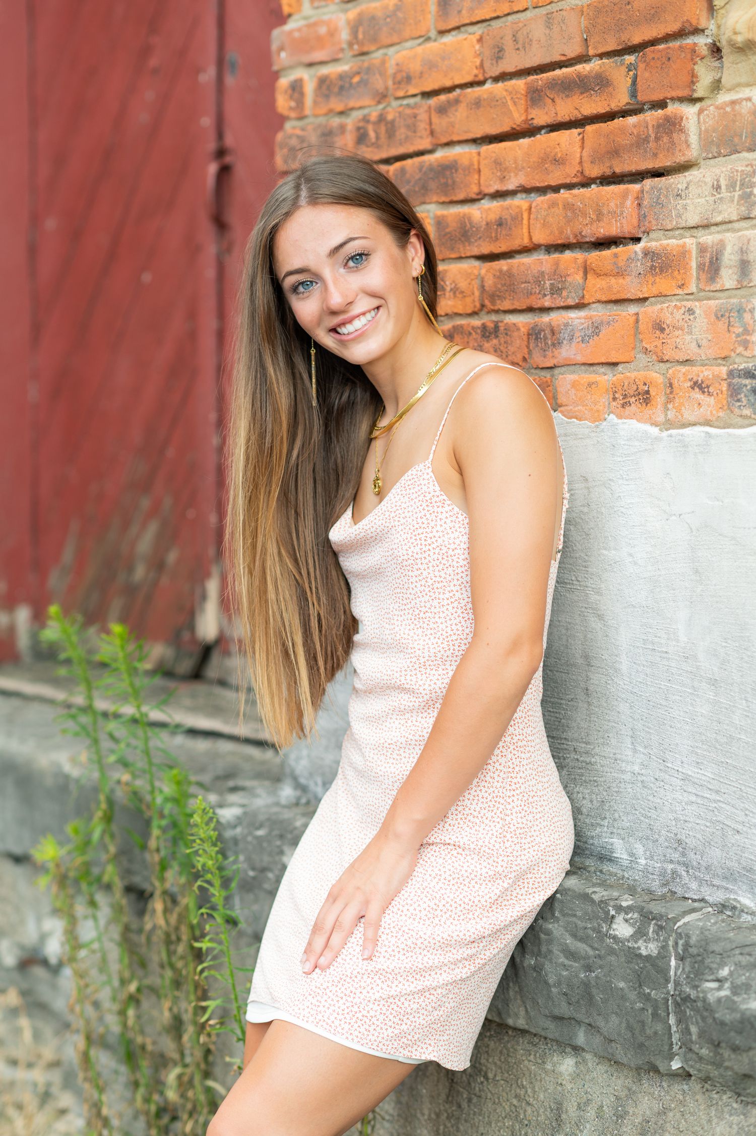 Pink sleeveless top styled against rustic brick wall backdrop.