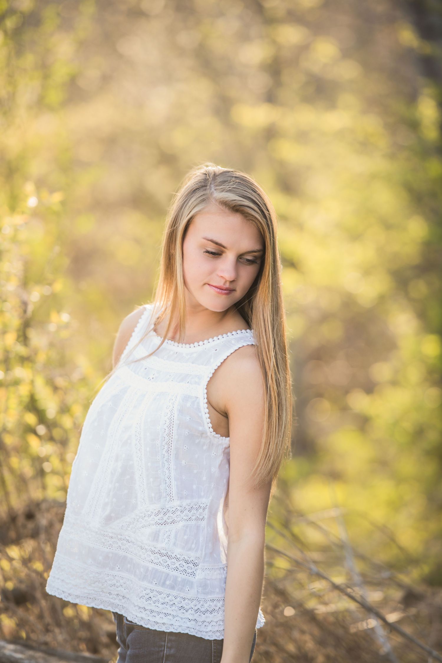 Outdoor photoshoot in a white lace top with natural bokeh background.