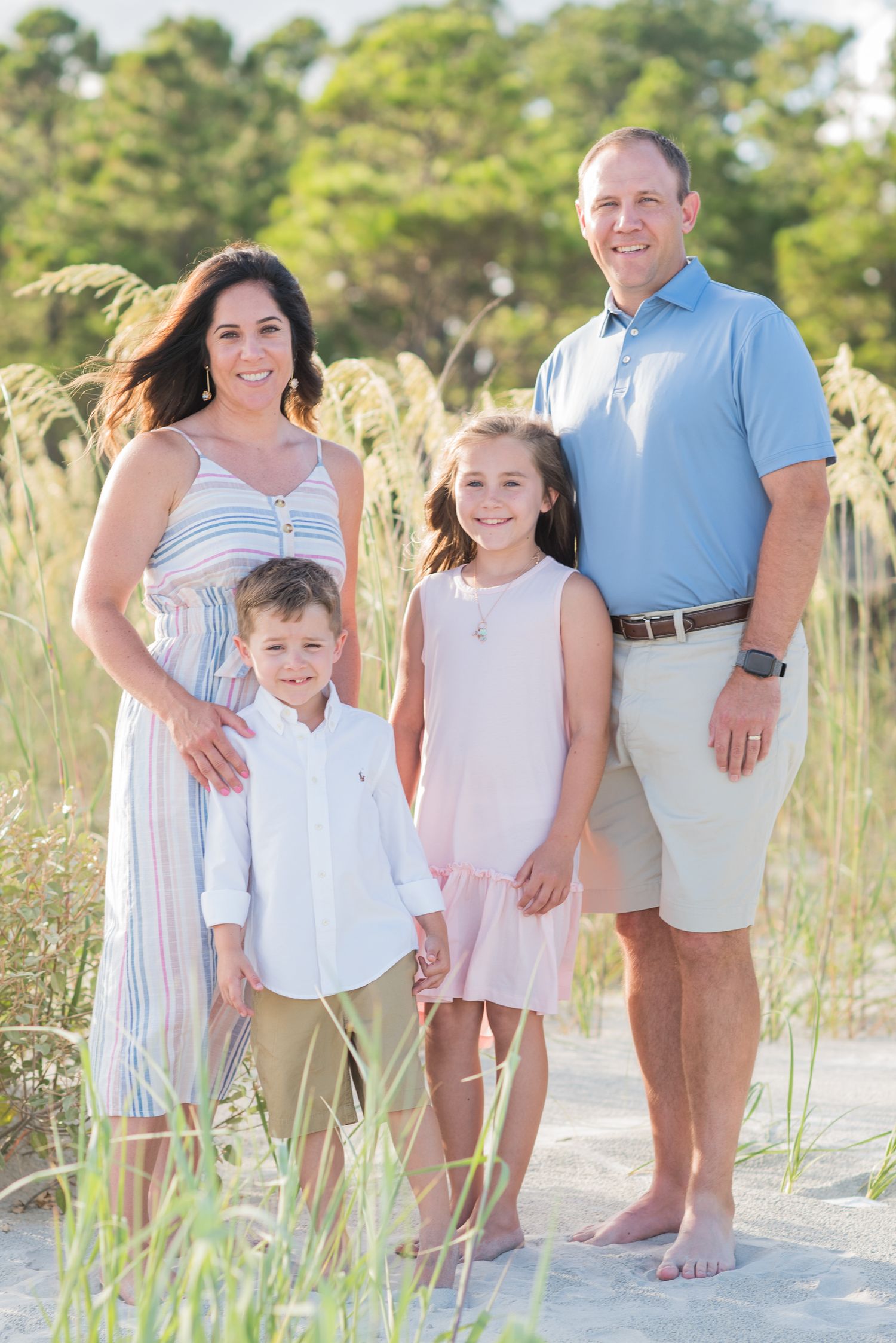 Family of four poses together on white sand beach surrounded by sea oats. St. Augustine