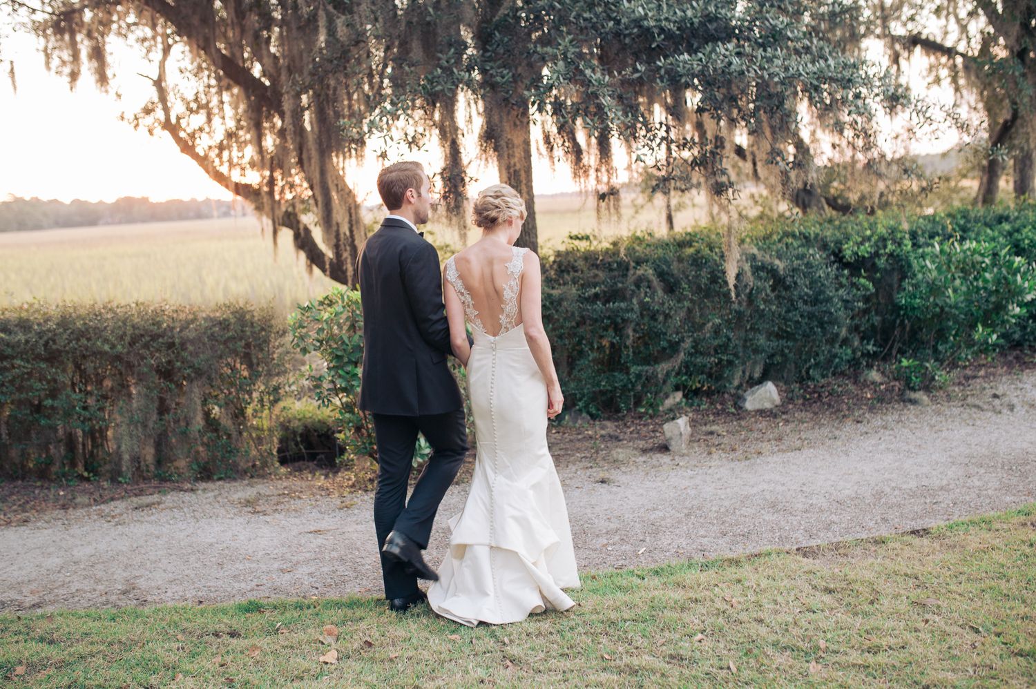 A couple shares a romantic moment under Spanish moss draped trees at sunset during their coastal Hilton Head wedding photoshoot.
