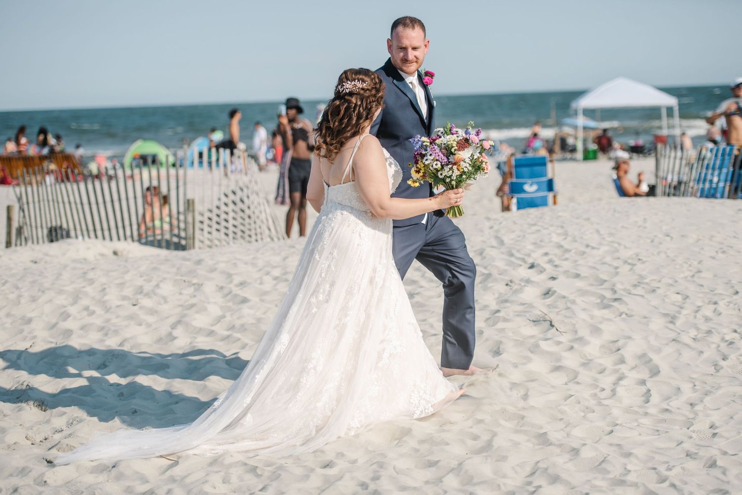 Wedding guests seated on a sandy beach with umbrellas and ocean views. Hilton Head wedding.