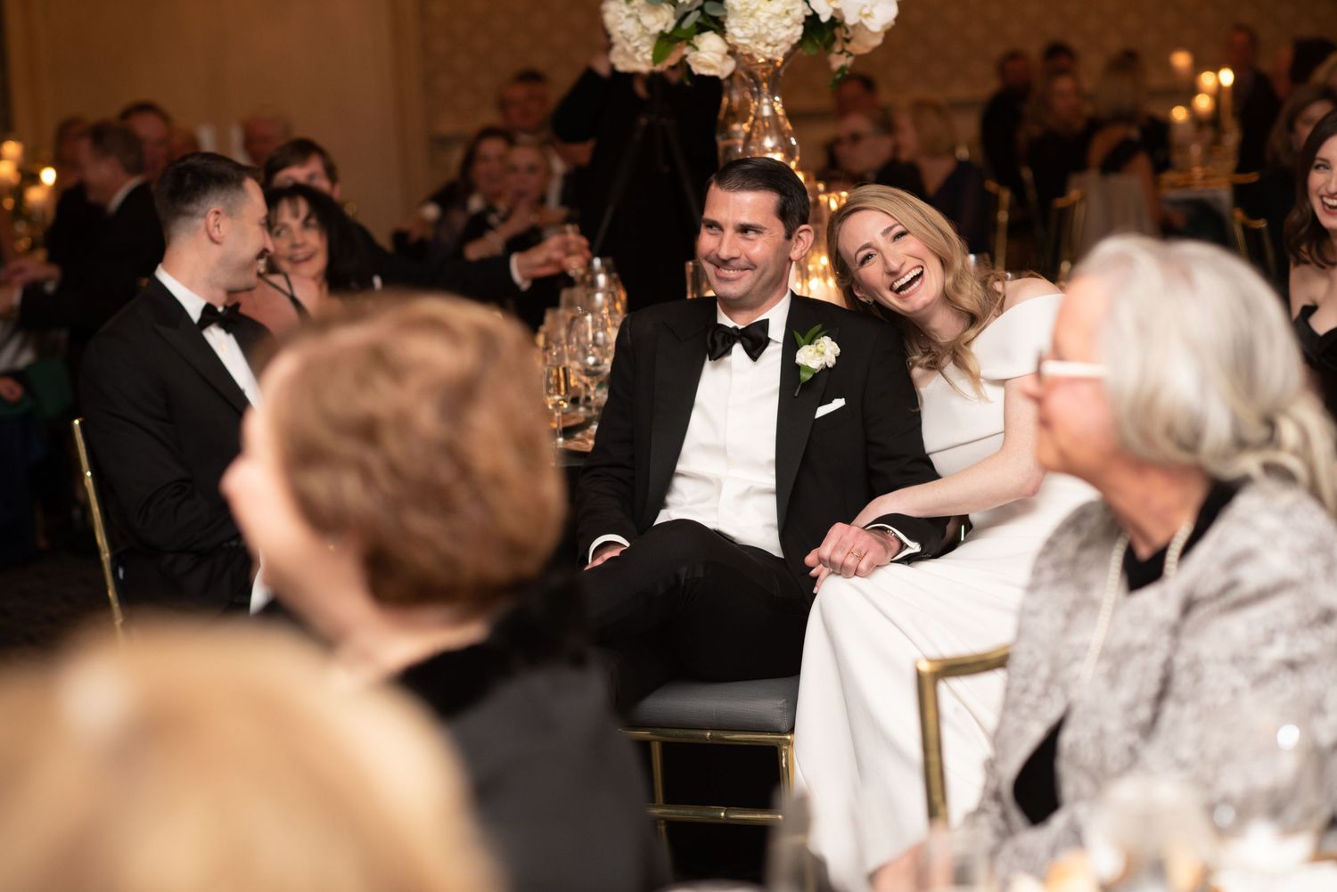 Wedding reception candid moments showing guests laughing and celebrating at elegant tables.