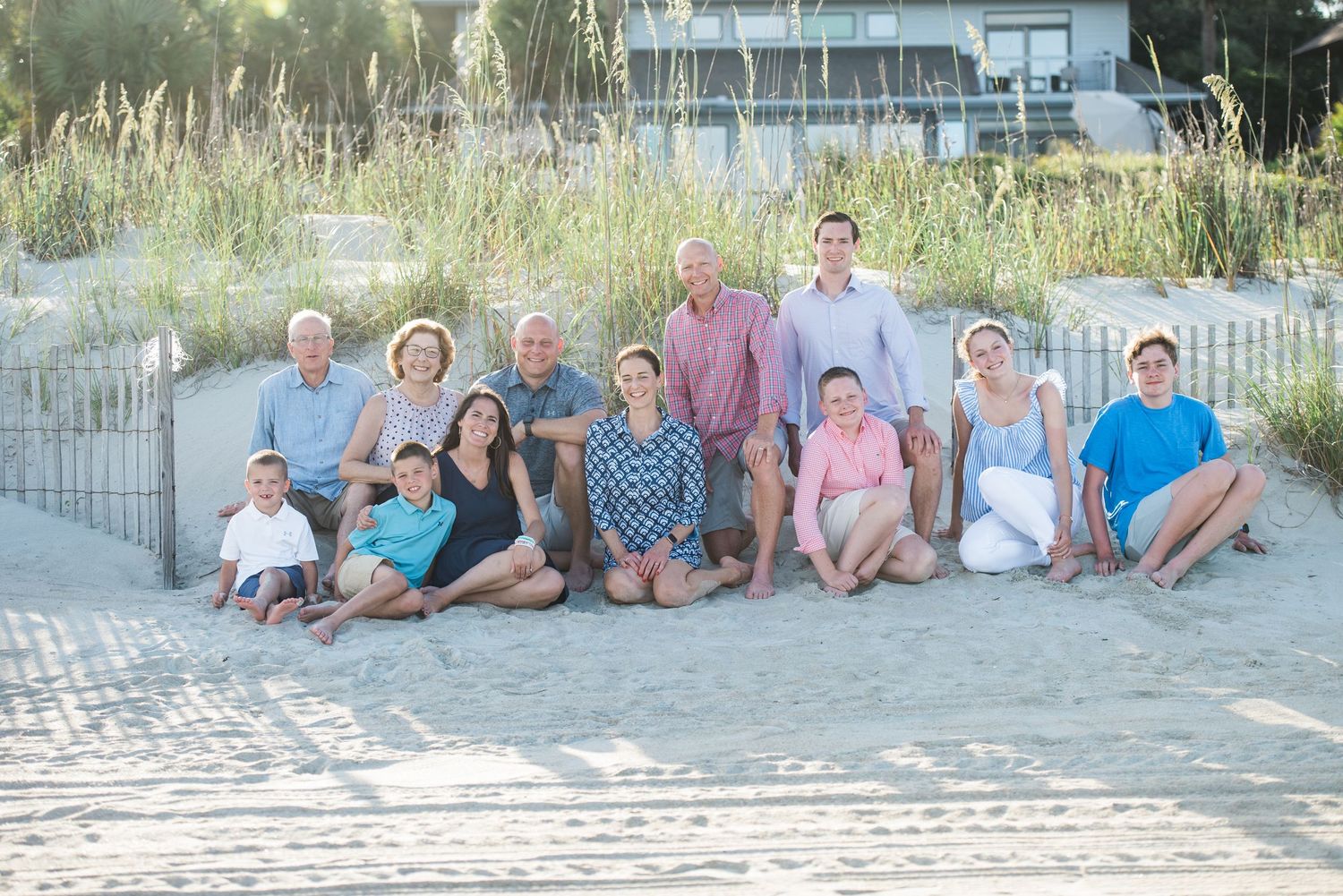 Multi-generational beach portrait with coastal vegetation and wooden walkway visible.Hammock Beach, Sea Pines coastal photography.