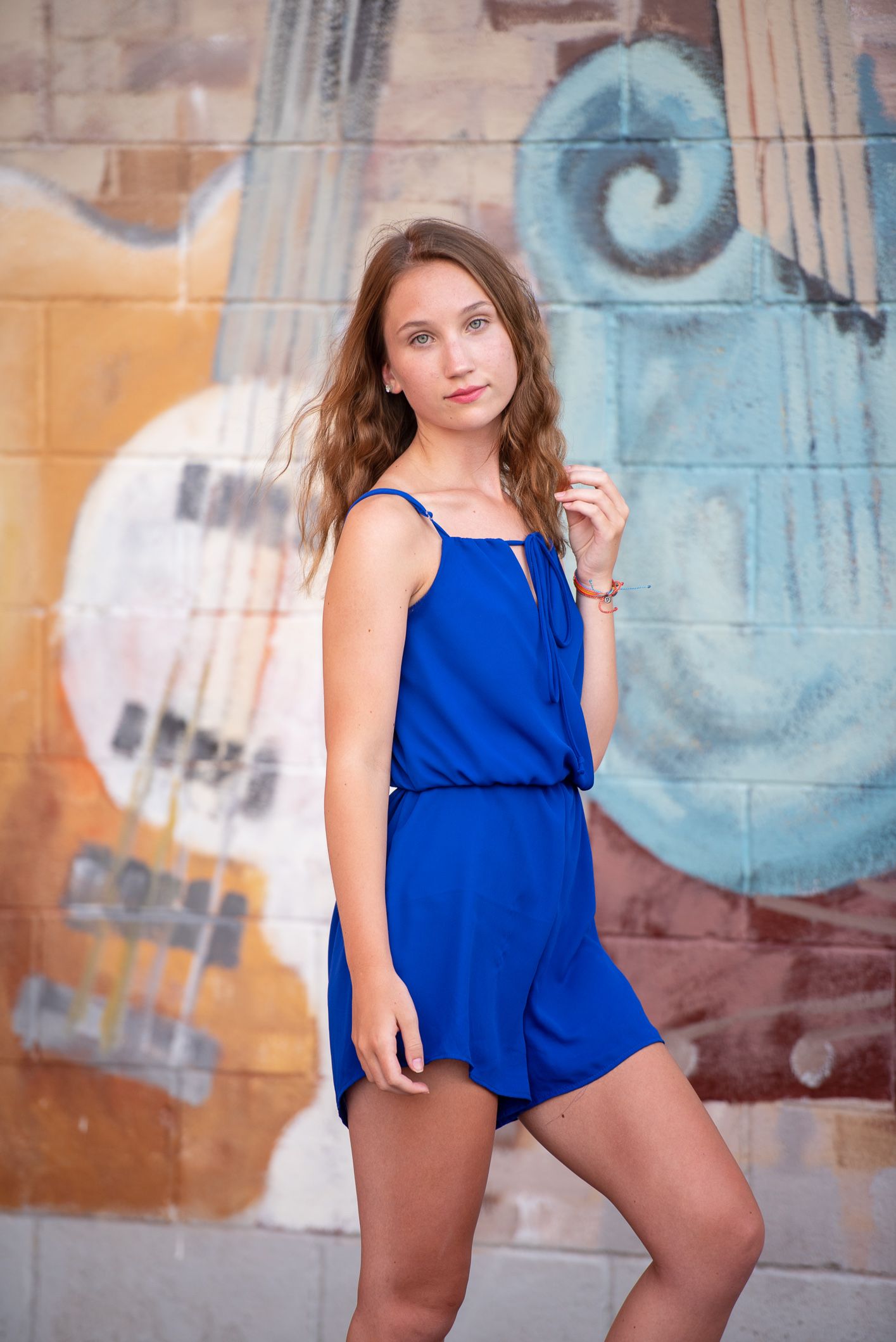 A series of fashion portraits against a graffiti wall showcasing a vibrant blue outfit in different poses.