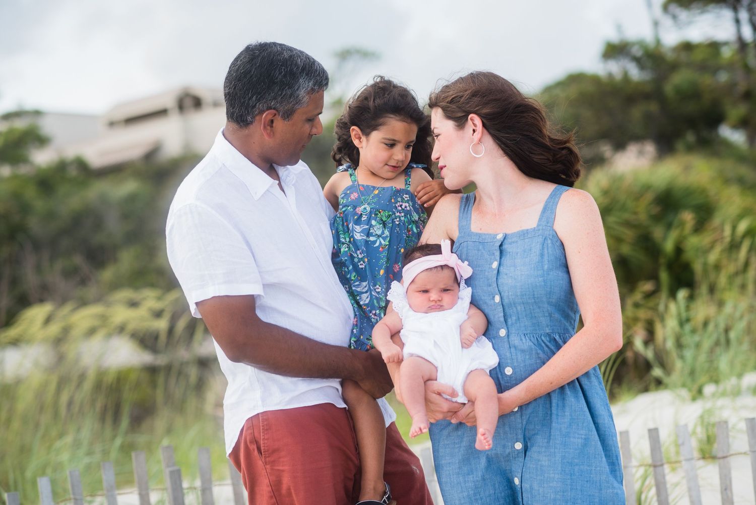 A family shares a tender moment together on a beach path with palm trees in the background. Flagler Beach portrait.