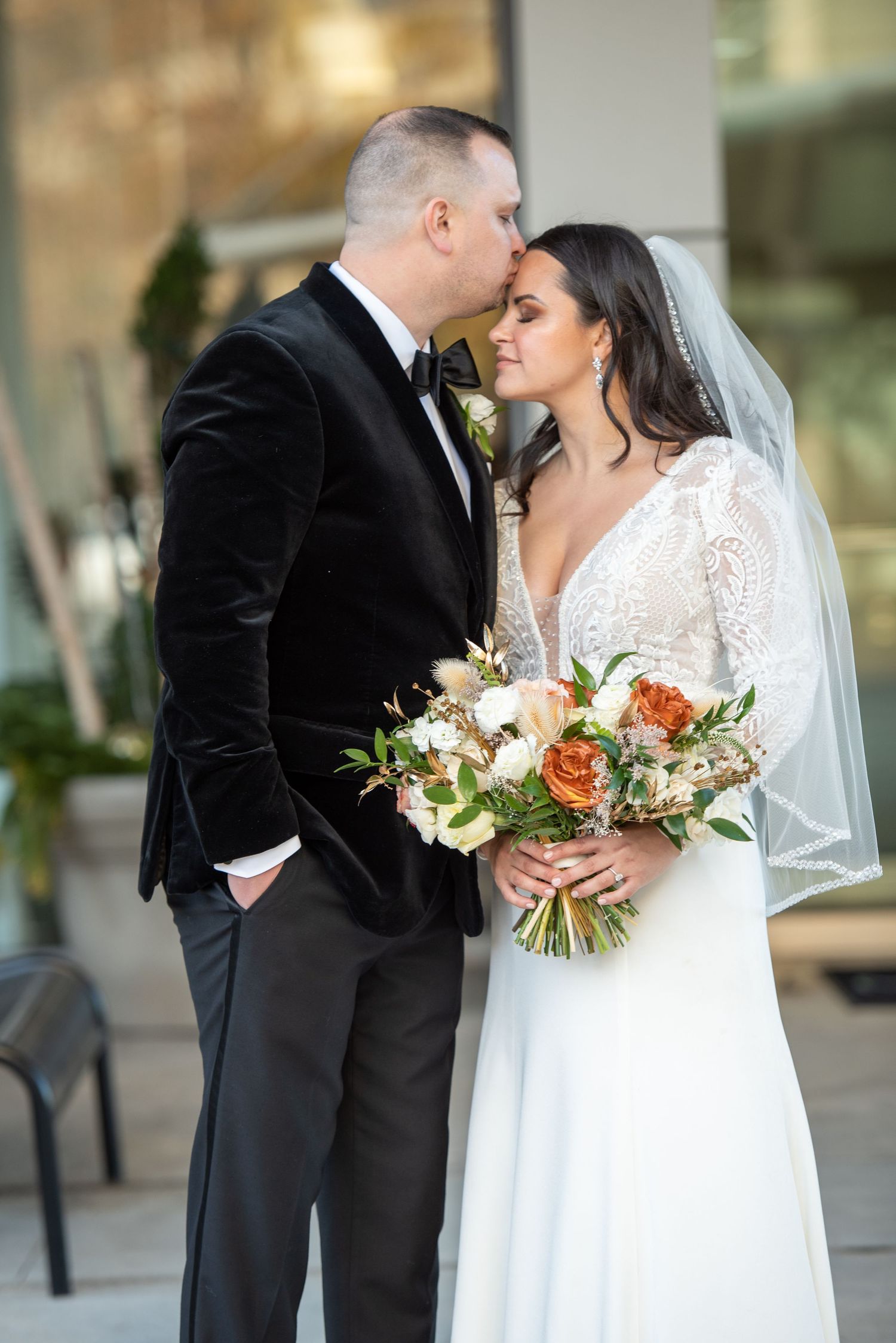 A tender wedding moment captured with a beautiful bouquet of peach roses and white flowers.