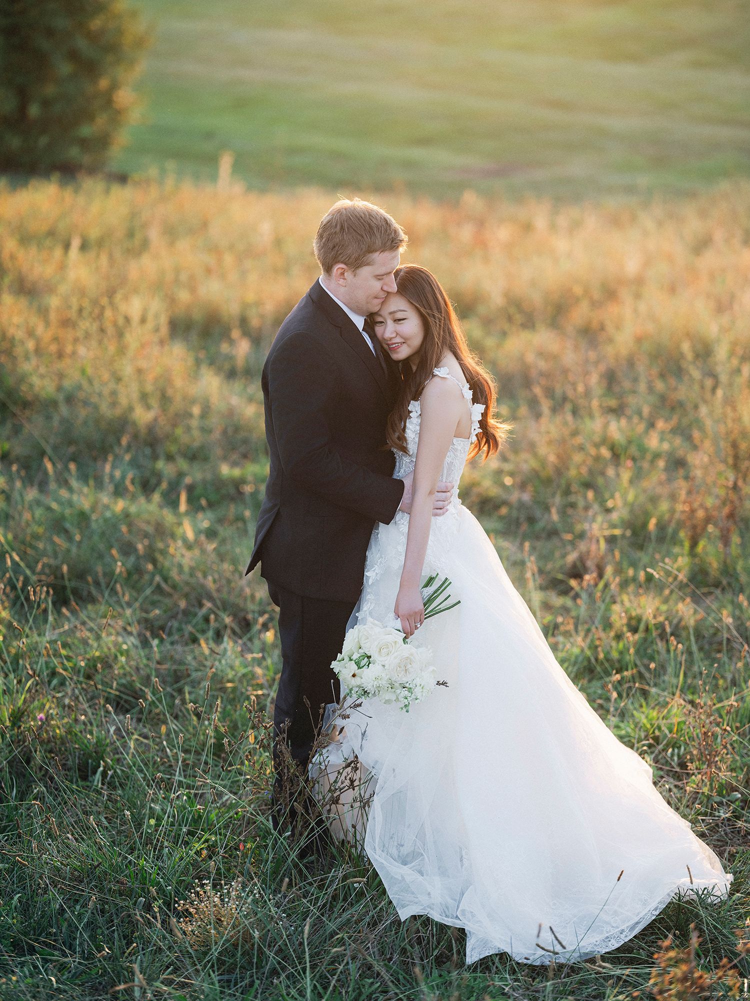 Romantic sunset wedding photos in a golden field with flowing white dress. NYC wedding photographer.