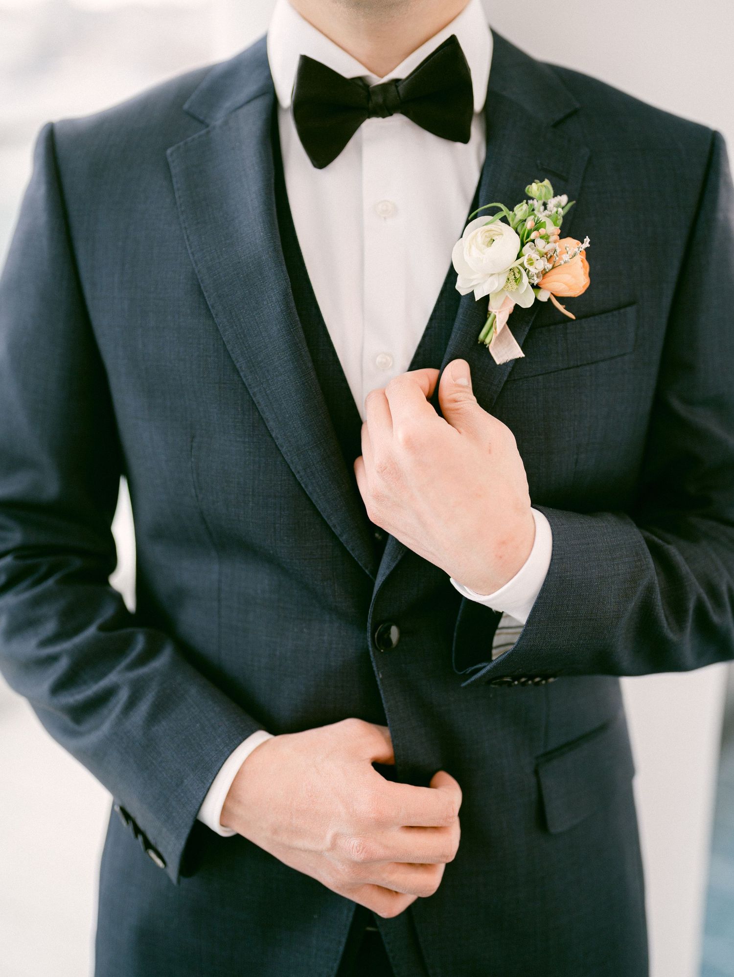 Close-up details of groom's formal black tuxedo with white boutonniere.