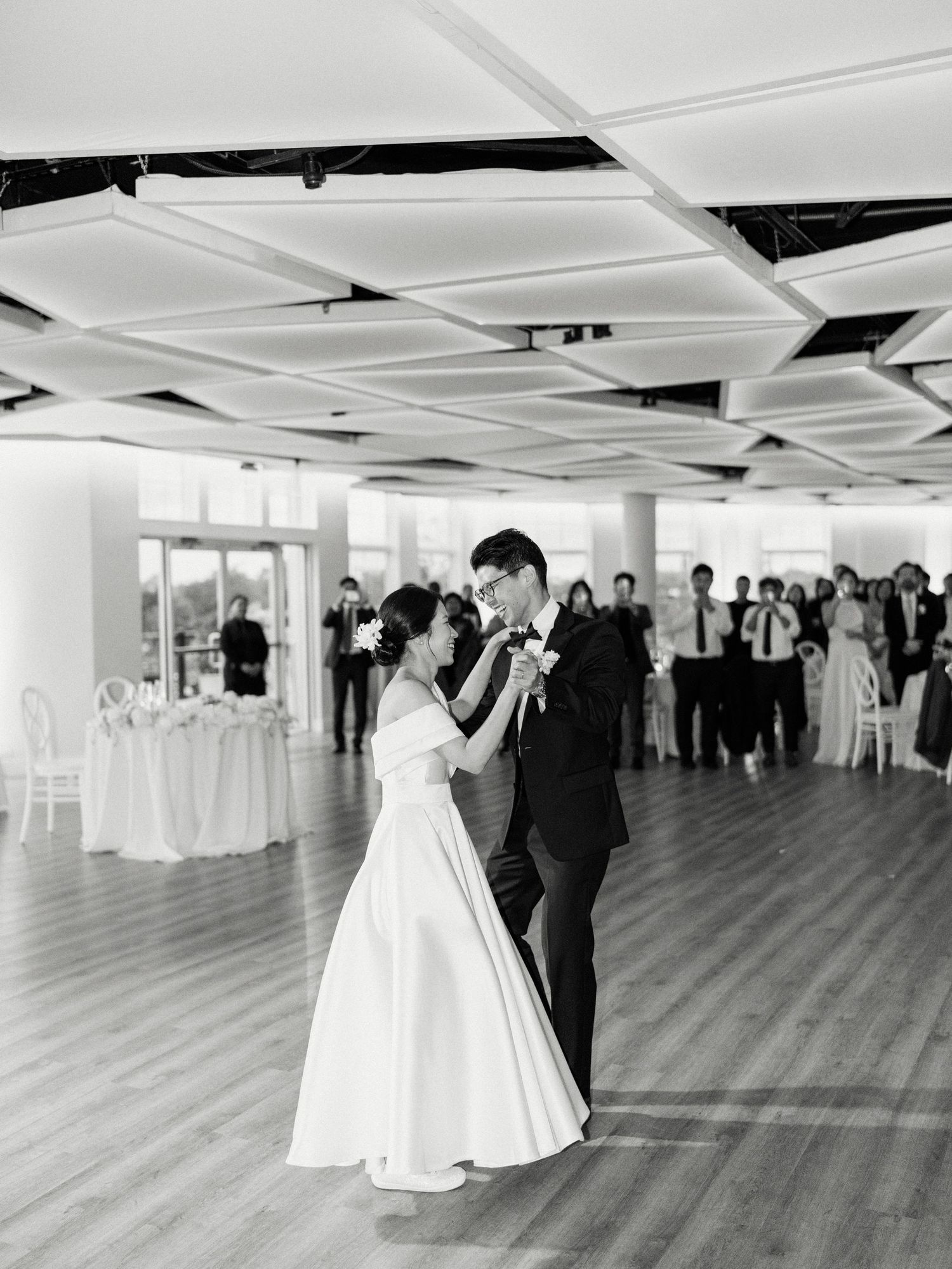 Wedding couple shares their first dance in a spacious white reception hall.