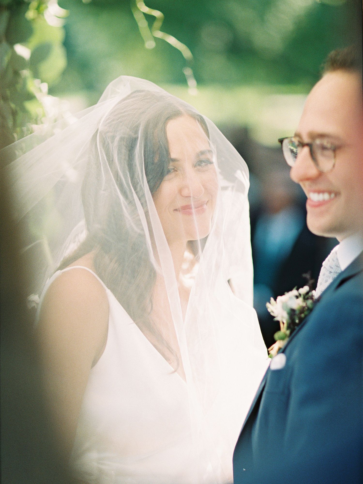 Intimate moment captured between couple during sunlit outdoor wedding ceremony.