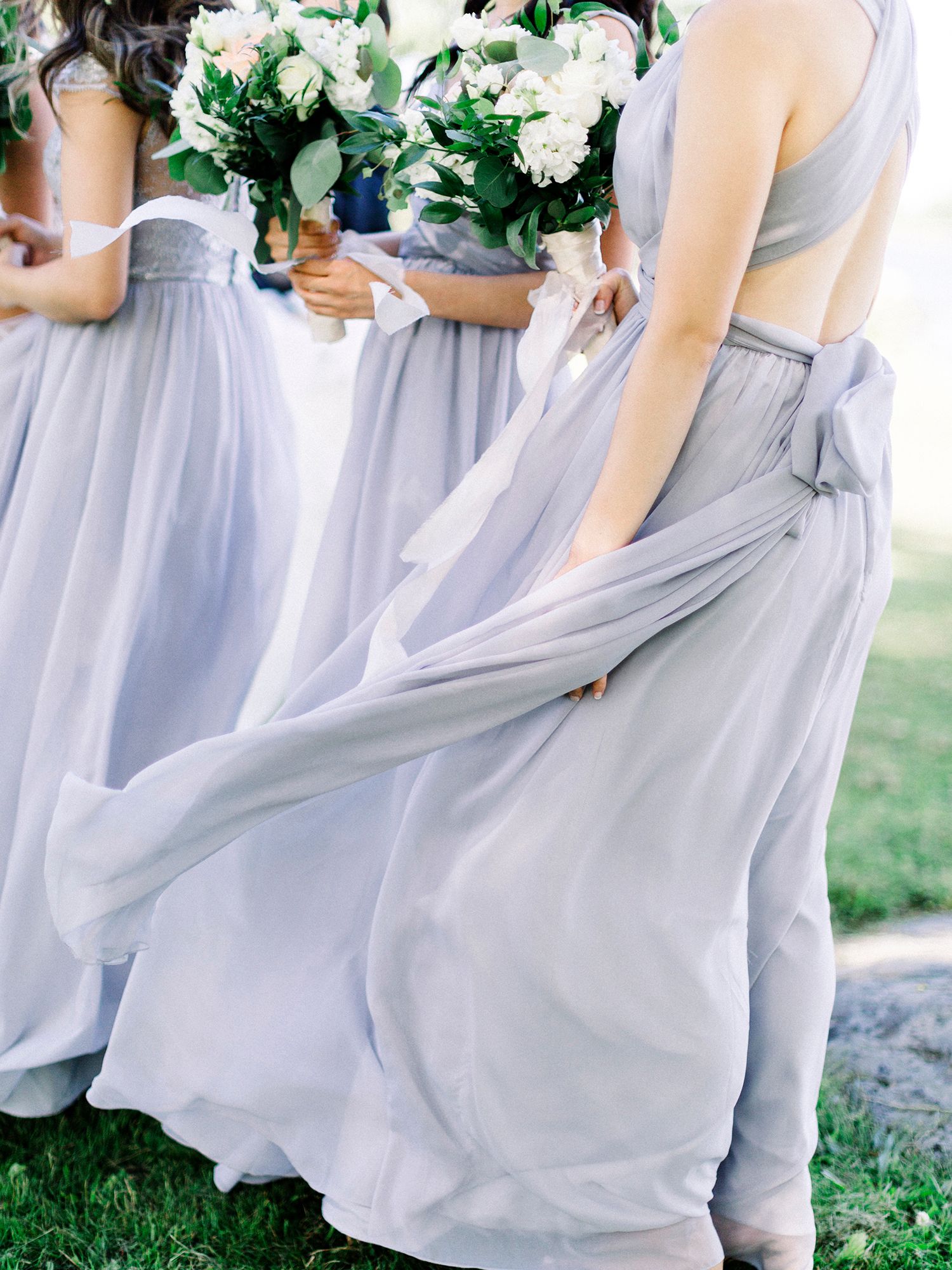 Bridesmaids in flowing light blue dresses holding white bouquets.