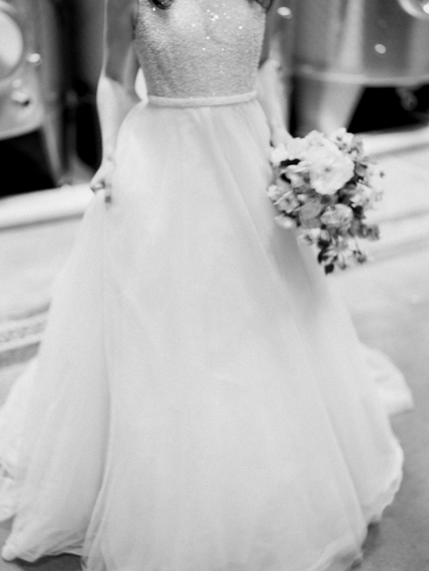 Close-up details of a flowing white wedding dress with delicate lace and tulle fabric.