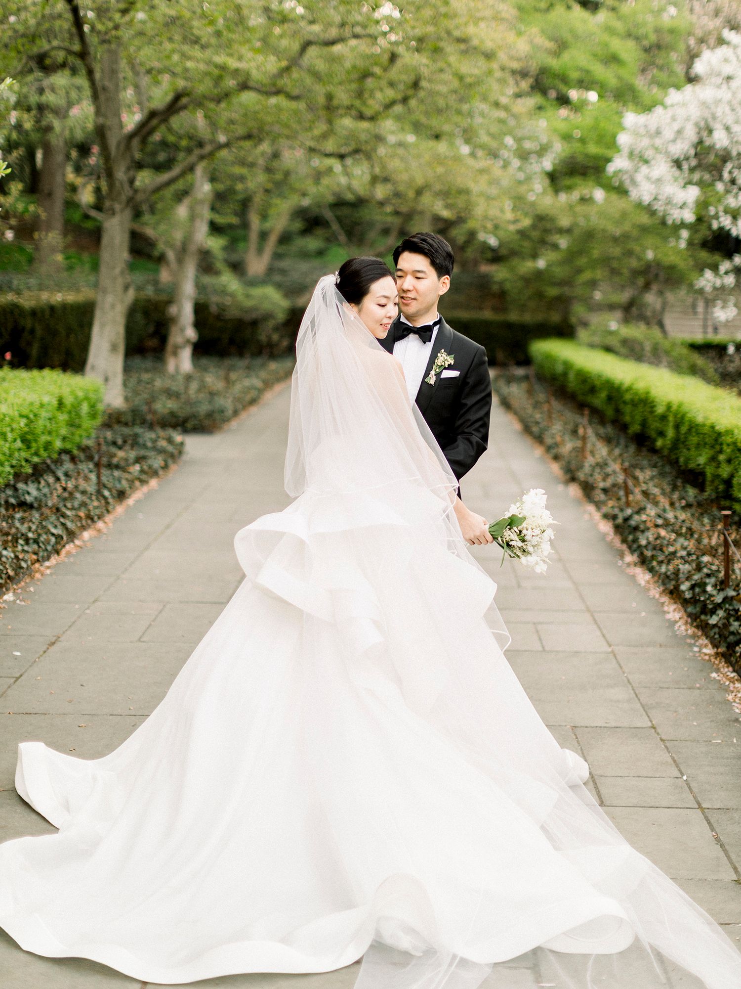 Elegant wedding photos on stone pathway with dramatic flowing white dress. NYC wedding photographer.